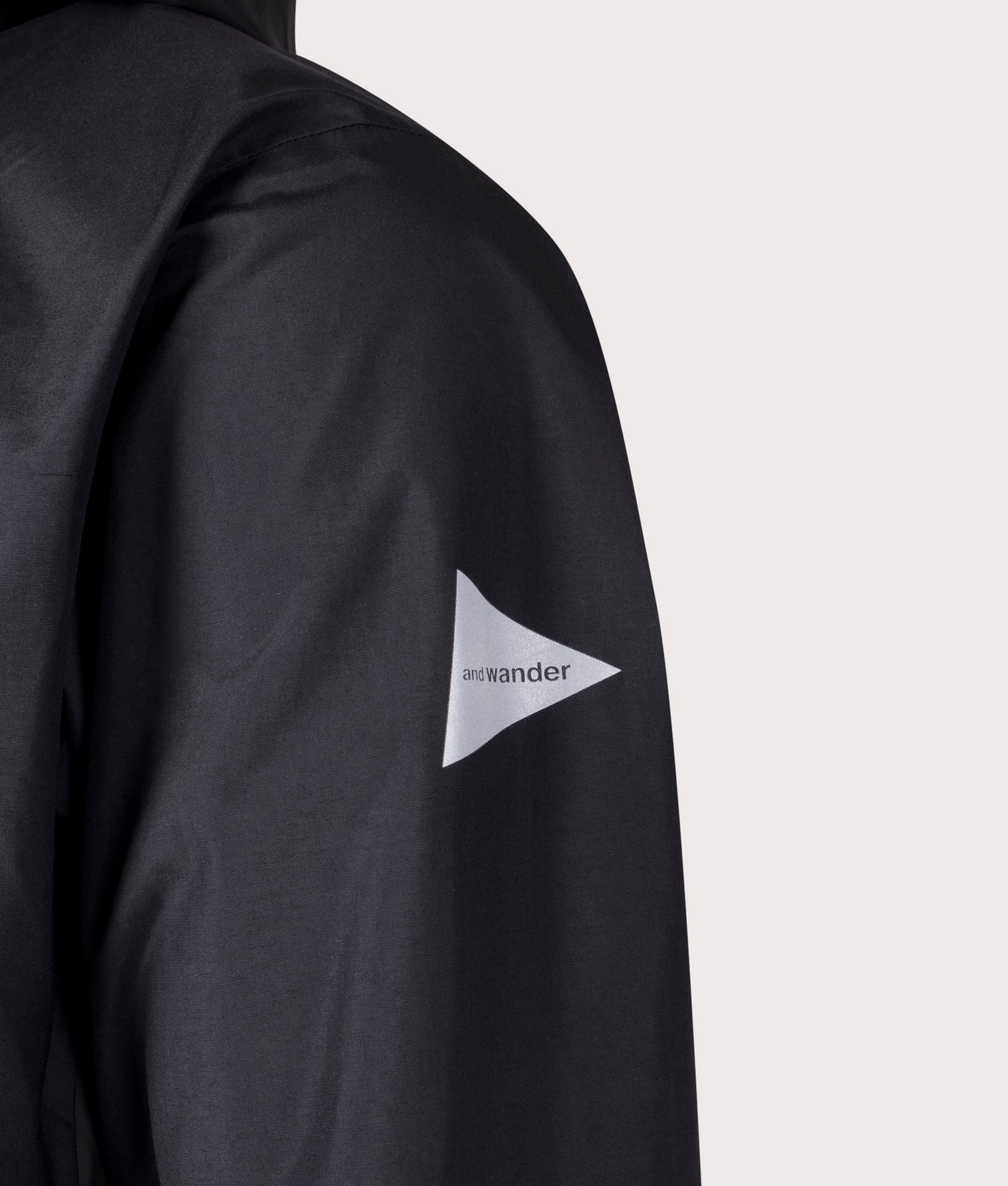 and Wander 2.5L Hiker Rain Jacket in Black. Shot at EQVVS. Left arm logo shot 