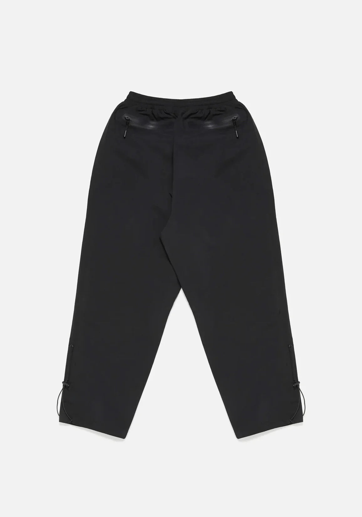 Loose Fit V2 Shell Track Pants in Black by MKI MIYUKI ZOKU at EQVVS. Flat Back Shot. 