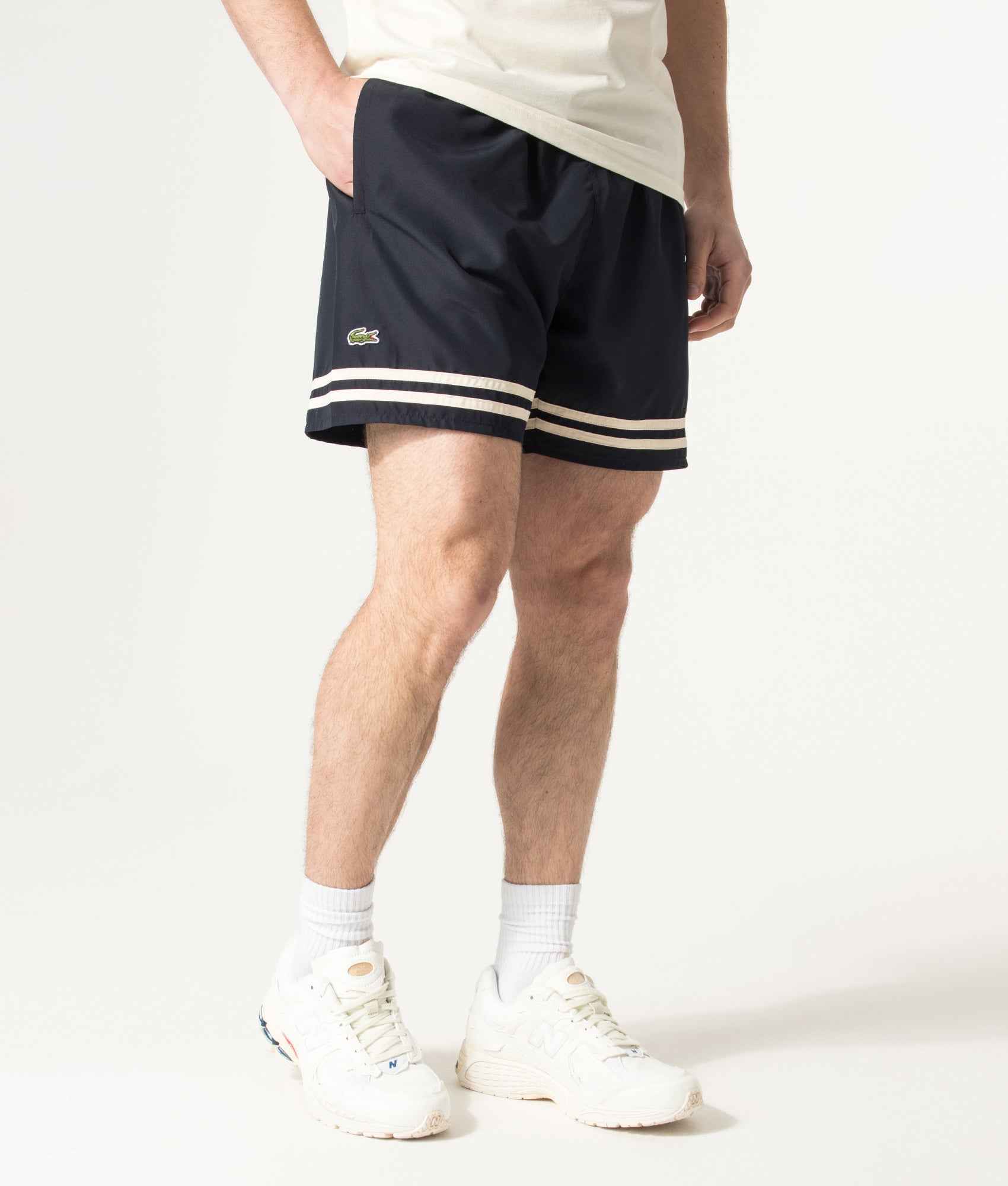 Lacoste Mid Length Contrast Stripe Swim Shorts in Blackbird and Naturel Clair at EQVVS Menswear. Angled model front shot.