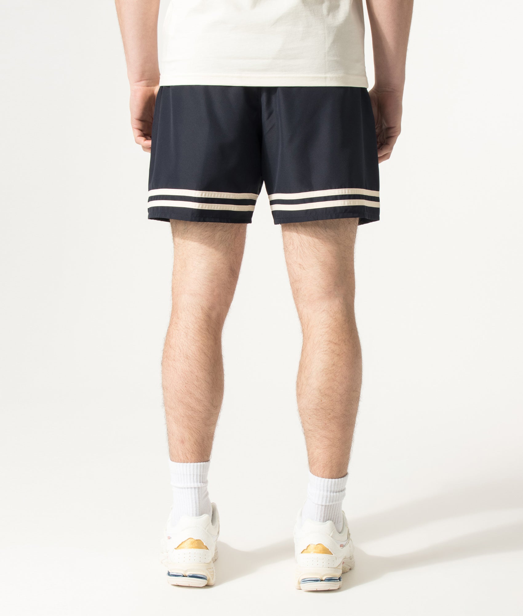 Lacoste Mid Length Contrast Stripe Swim Shorts in Blackbird and Naturel Clair at EQVVS Menswear. Angled model back shot.