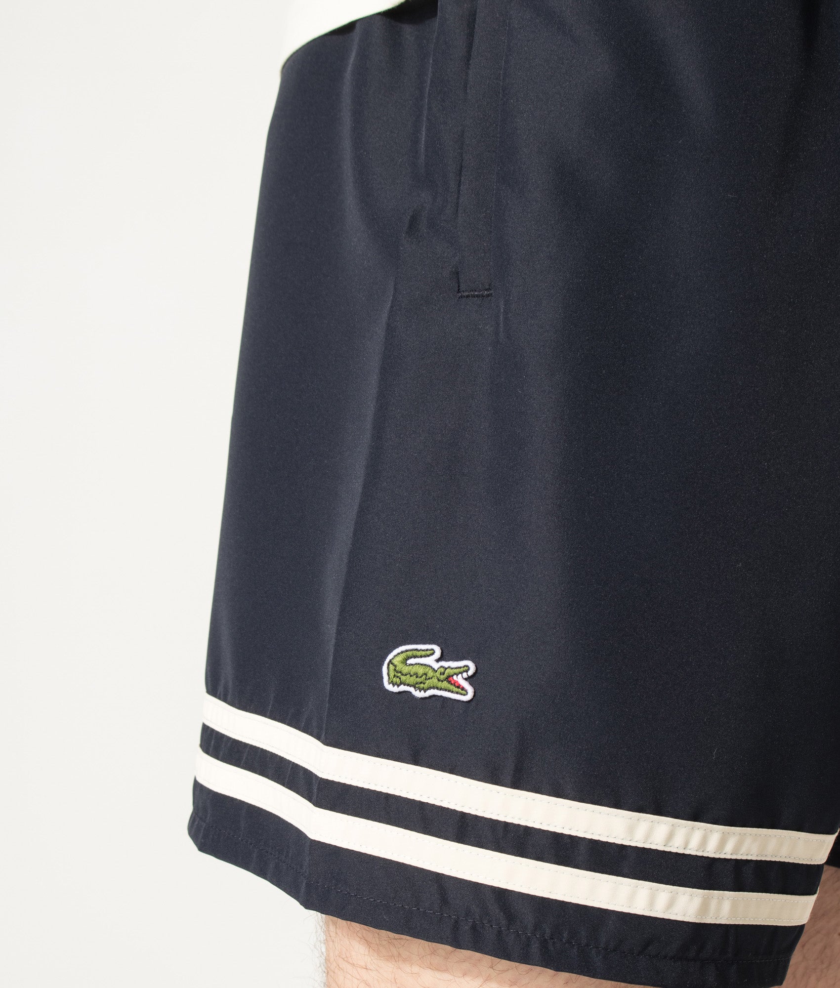 Lacoste Mid Length Contrast Stripe Swim Shorts in Blackbird and Naturel Clair at EQVVS Menswear. Detail shot.