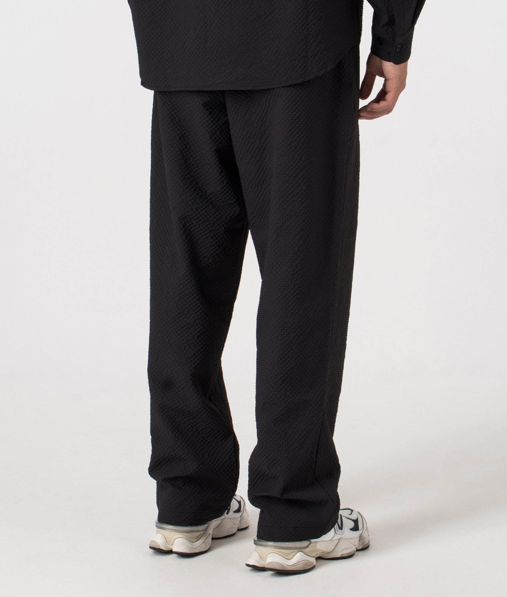 MKI Relaxed Fit Seersucker Trousers in Black. Back angle model shot at EQVVS.