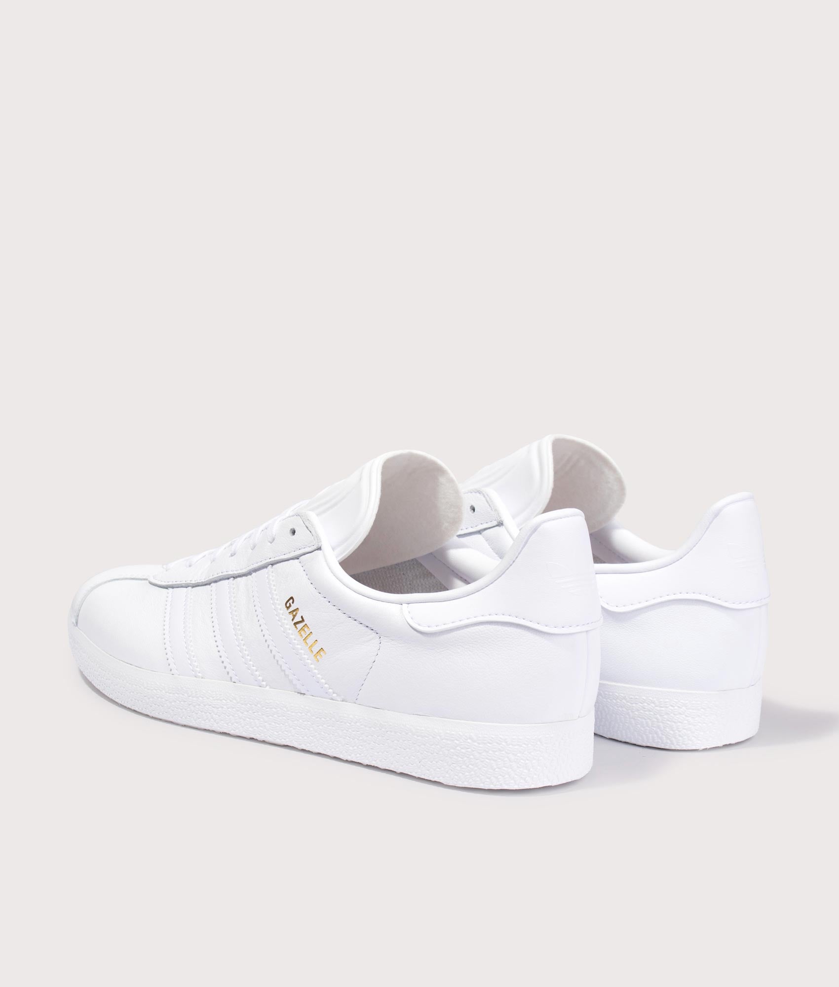adidas Originals Gazelle Trainers in White/White/Gold Metallic at EQVVS Menswear. Angled back shot.