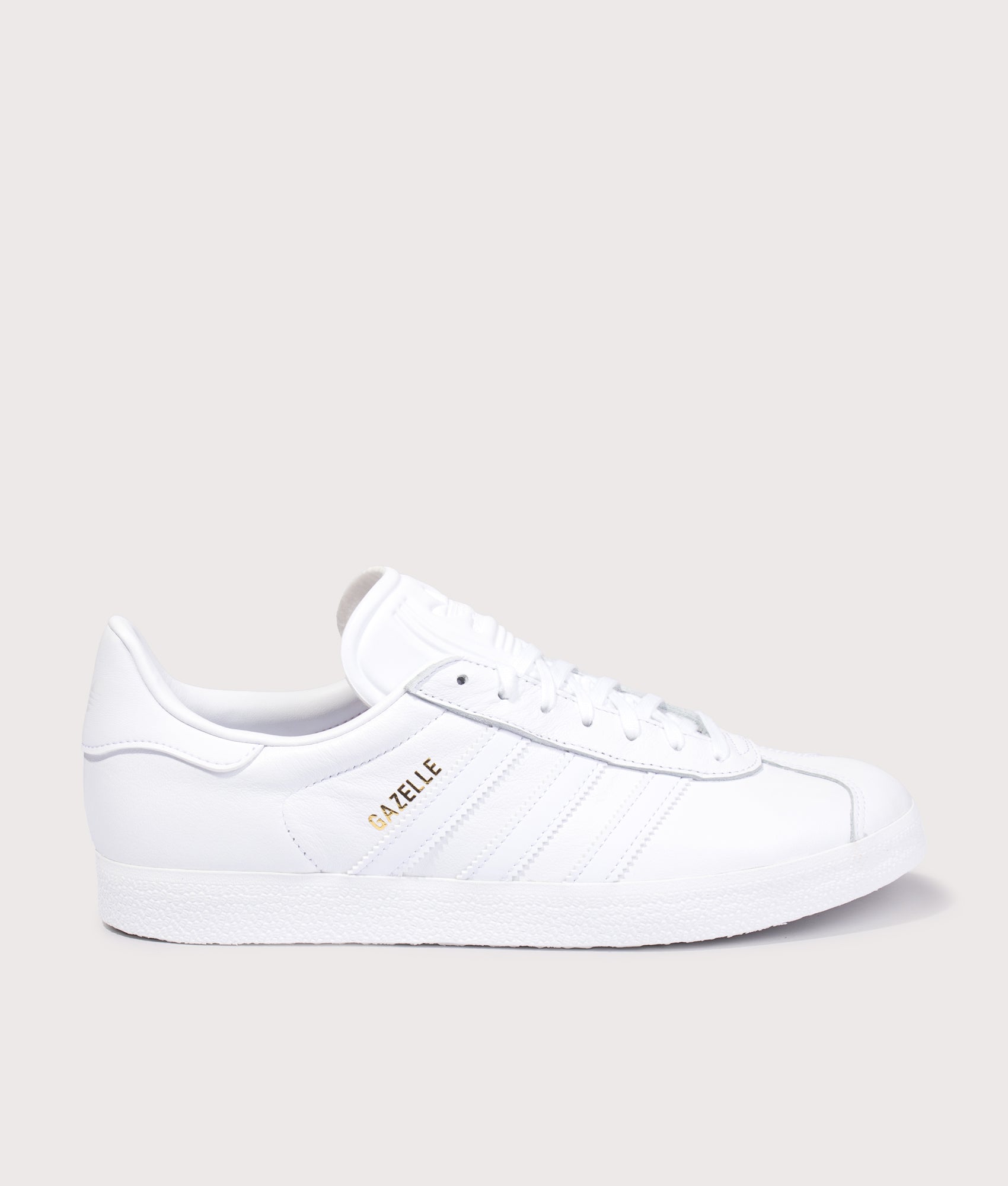 adidas Originals Gazelle Trainers in White/White/Gold Metallic at EQVVS Menswear. Side shot.