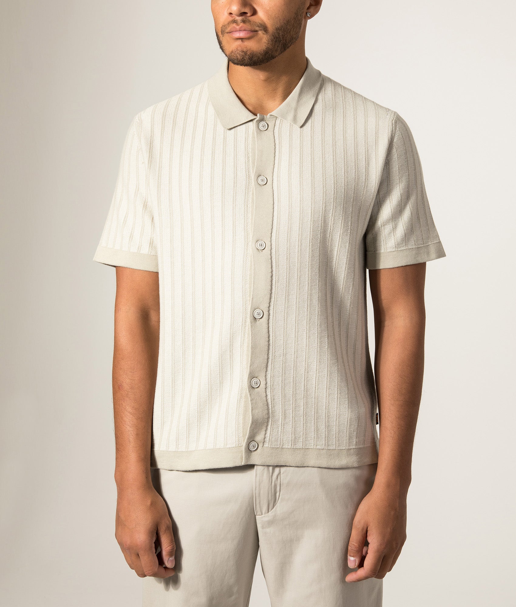 BOSS Relaxed Fit Kodd Knitted Polo Shirt in Light Beige at EQVVS Menswear. Model front shot.