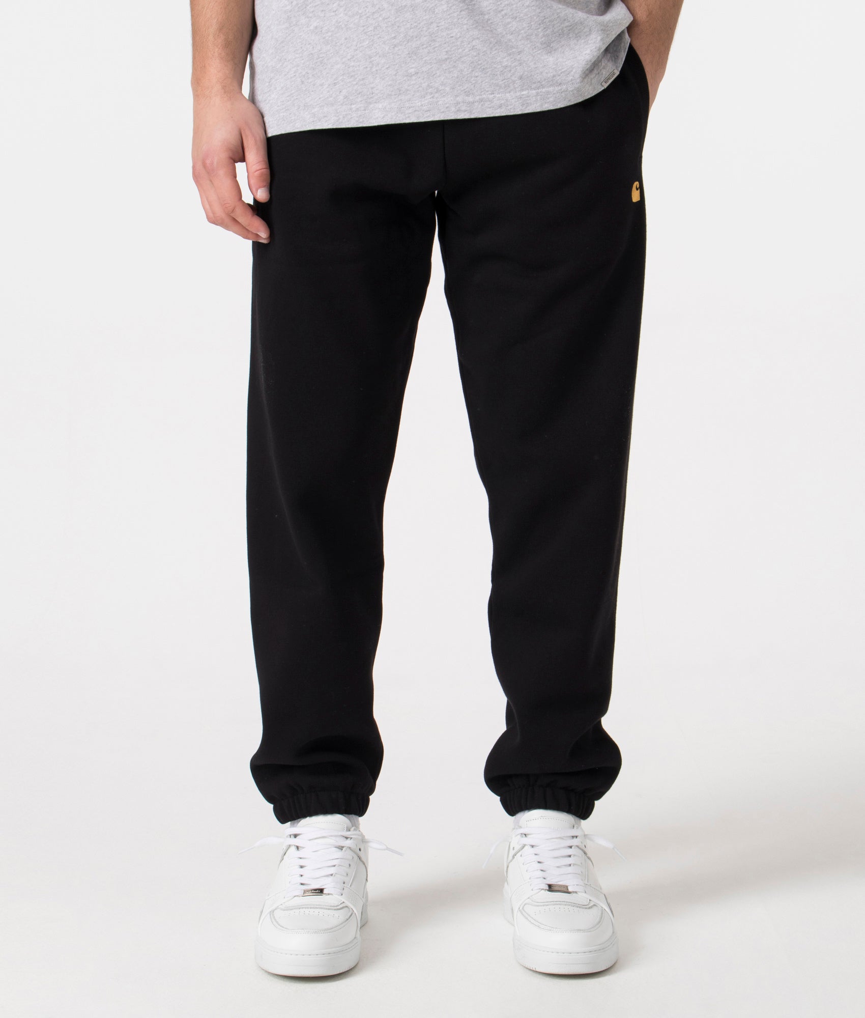 Carhartt WIP Relaxed Fit Chase Joggers in Black with Gold Carhartt 'C' Front Shot at EQVVS