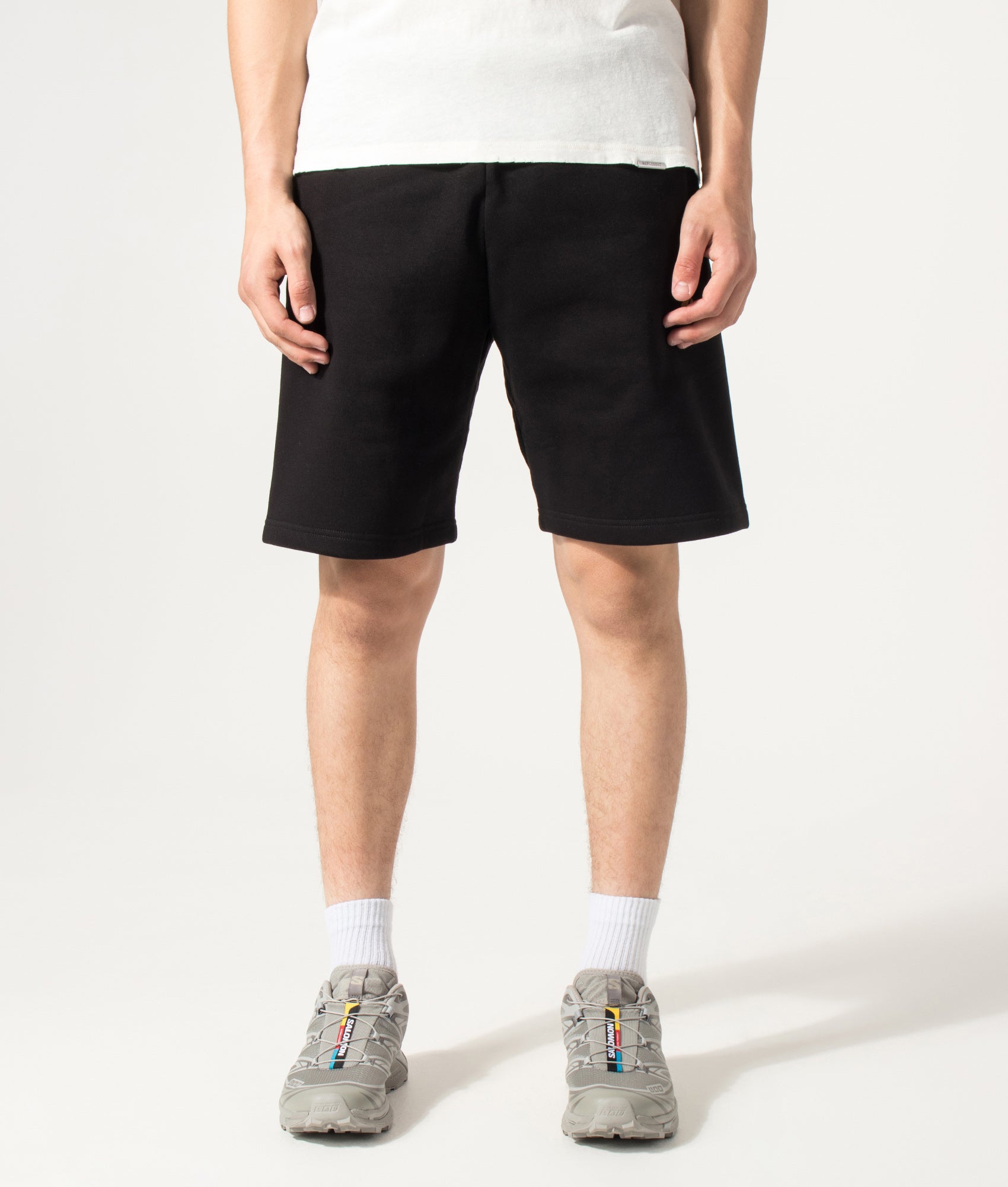 Carhartt WIP Loose Fit Chase Sweat Shorts in Black and Gold at EQVVS Menswear. Model front shot.