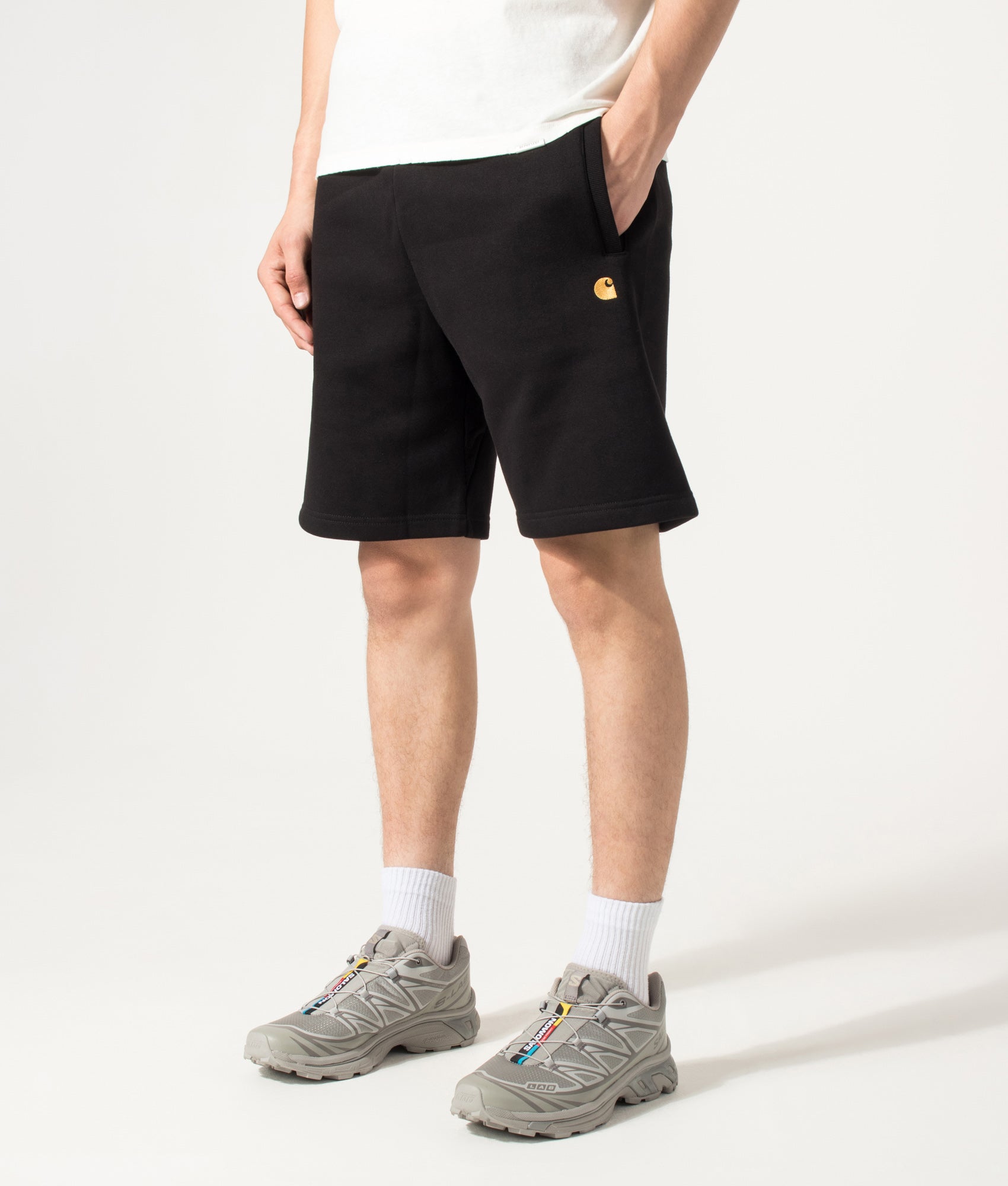 Carhartt WIP Loose Fit Chase Sweat Shorts in Black and Gold at EQVVS Menswear. Angled model front shot.