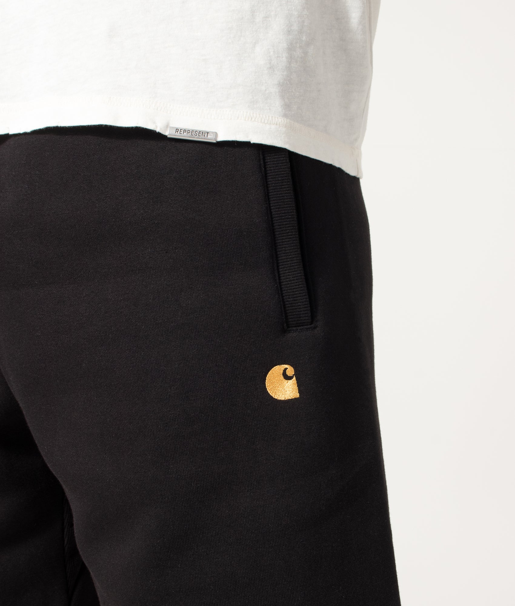 Carhartt WIP Loose Fit Chase Sweat Shorts in Black and Gold at EQVVS Menswear. Detail shot.