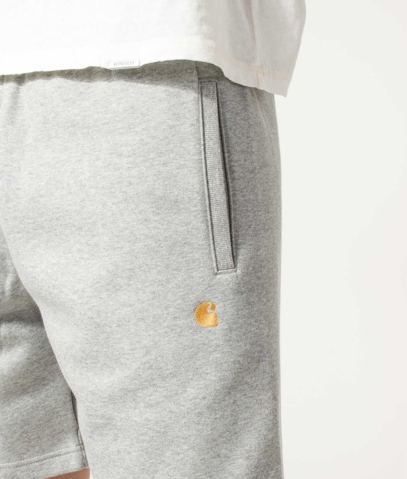 Carhartt WIP Loose Fit Chase Sweat Shorts in Grey Heather and Gold at EQVVS Menswear. Detail shot.