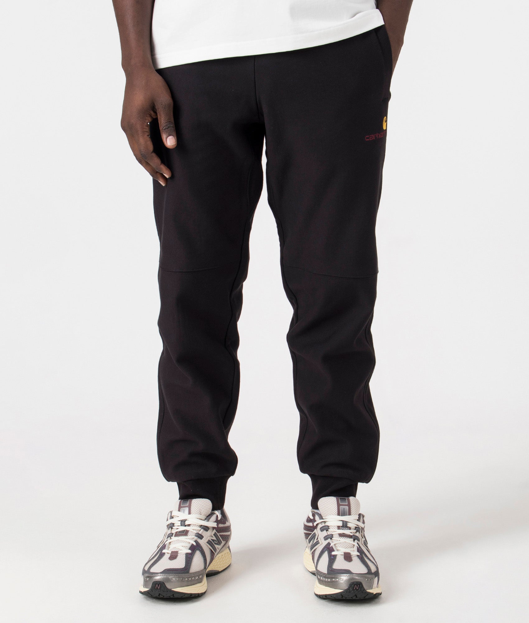 Carhartt WIP Relaxed Fit American Script Joggers in Black. Front angle model shot at EQVVS.