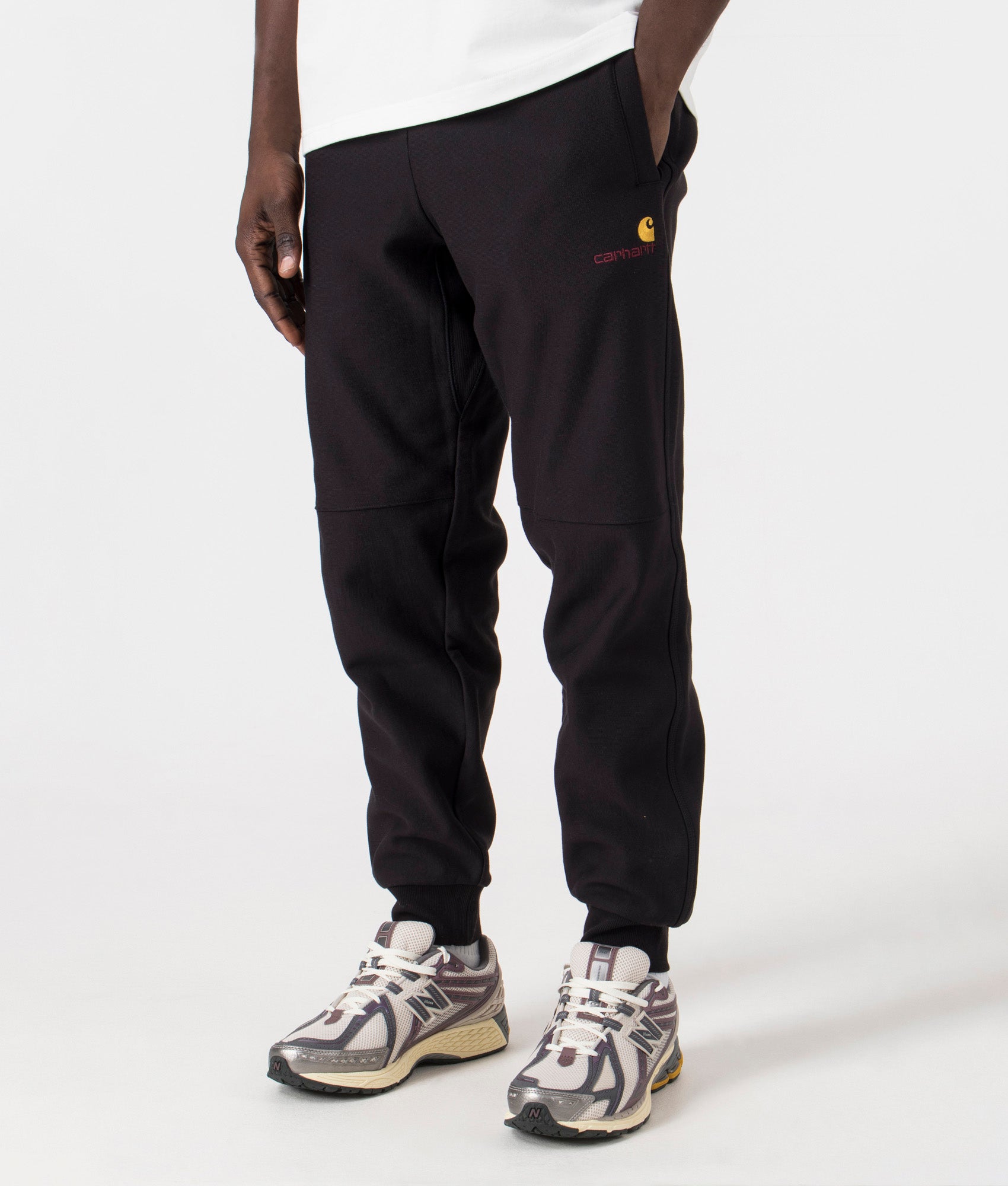 Carhartt WIP Relaxed Fit American Script Joggers in Black. Side angle model shot at EQVVS.