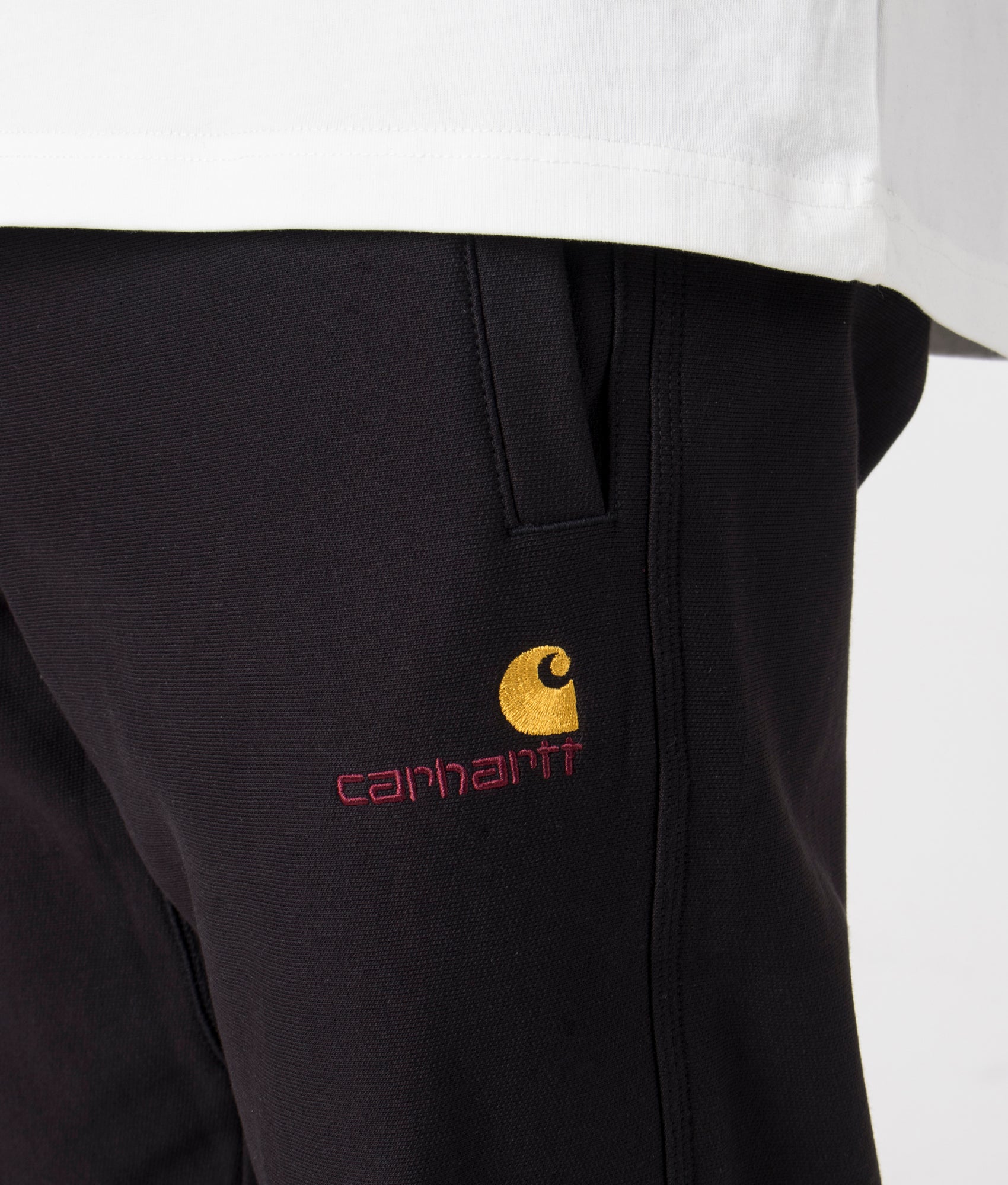 Carhartt WIP Relaxed Fit American Script Joggers in Black. Detail angle model shot at EQVVS.