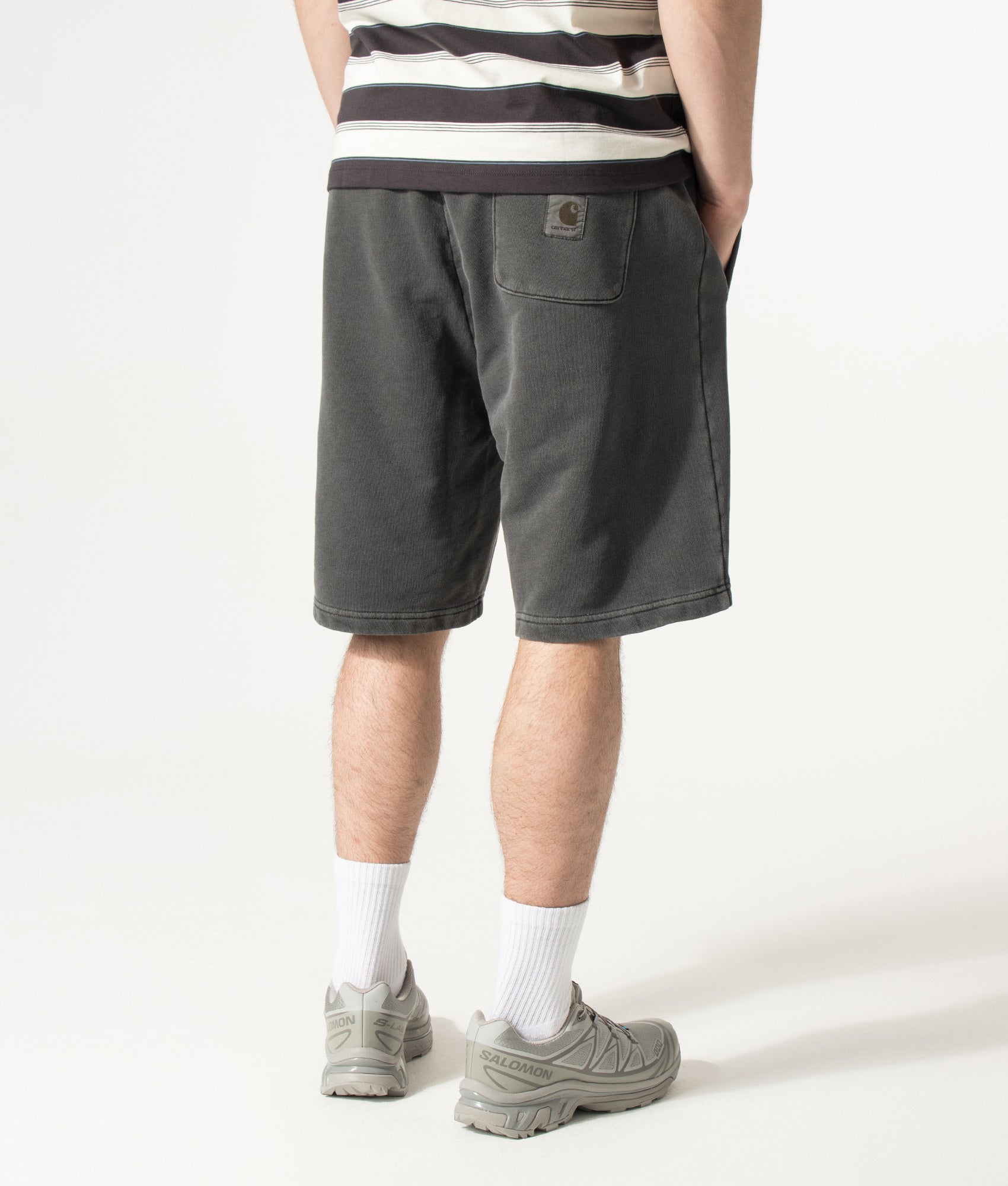Carhartt WIP Balloon Fit Nelson Sweat Shorts in Black at EQVVS Menswear. Angled model back shot.