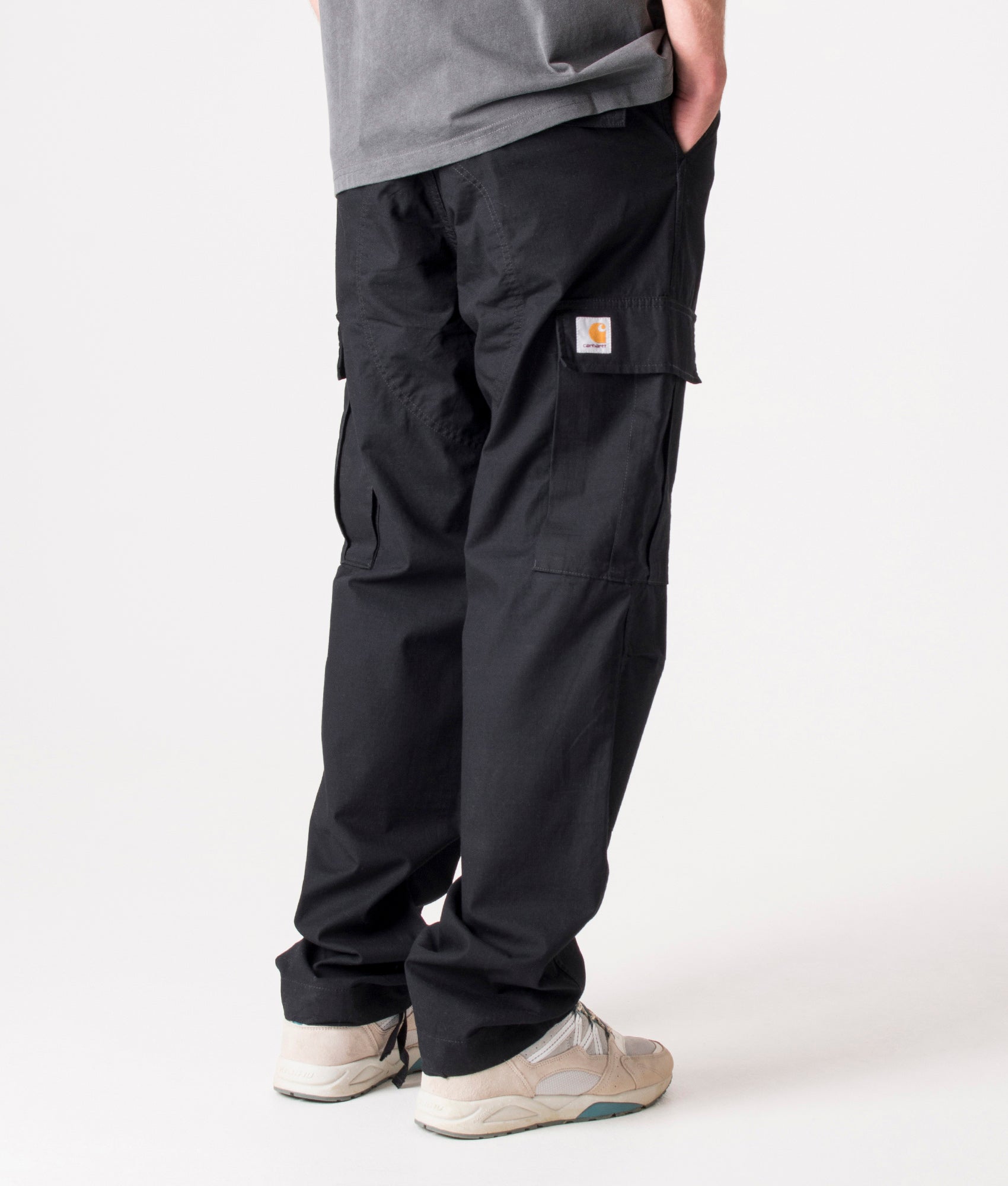 Carhartt Regular Fit Cargo Pants in Black at EQVVS Menswear. Angled model back shot.