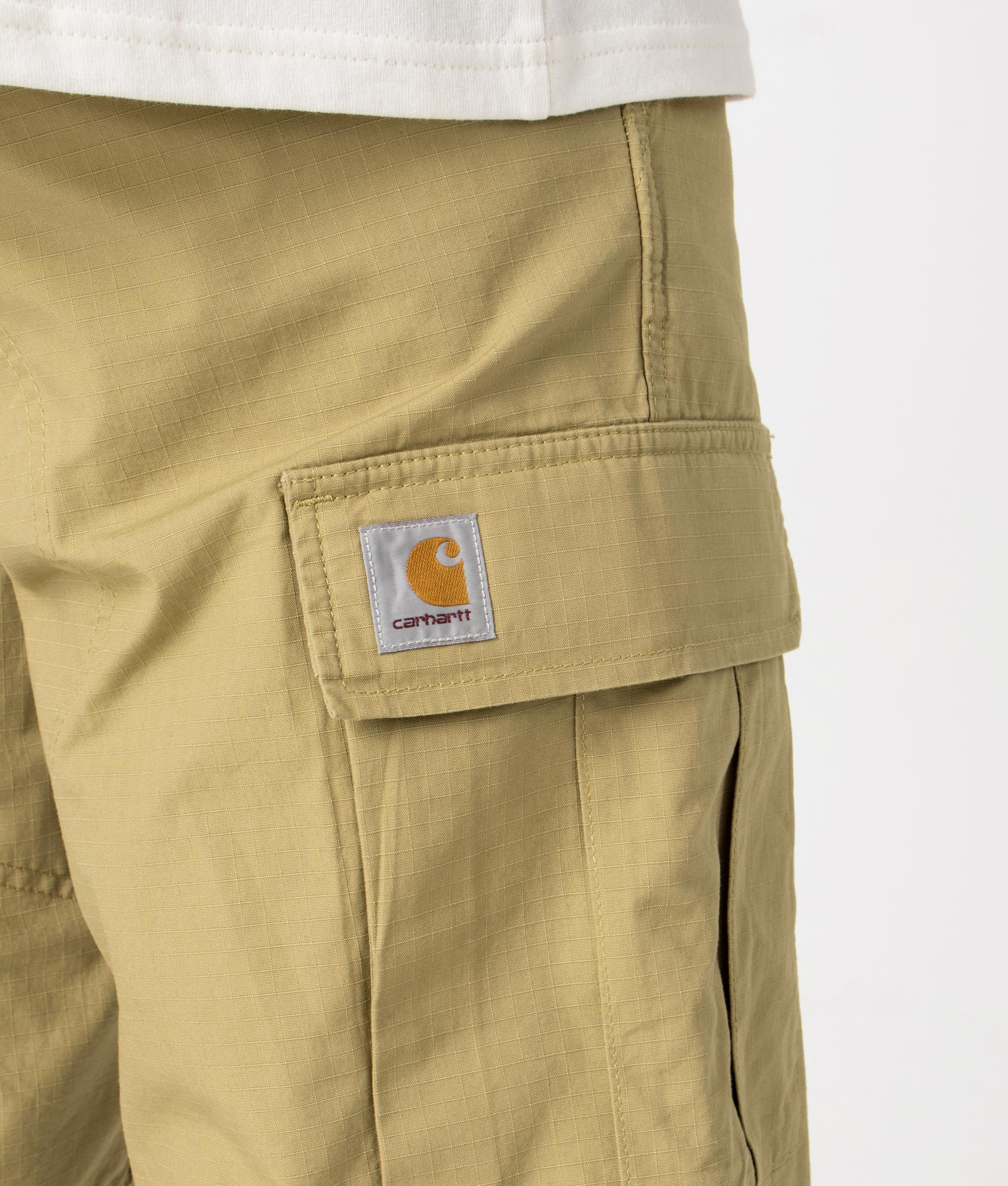 Carhartt WIP Regular Cargo Shorts in Agate Beige, 100% Cotton. Detail Model Shot at EQVVS
