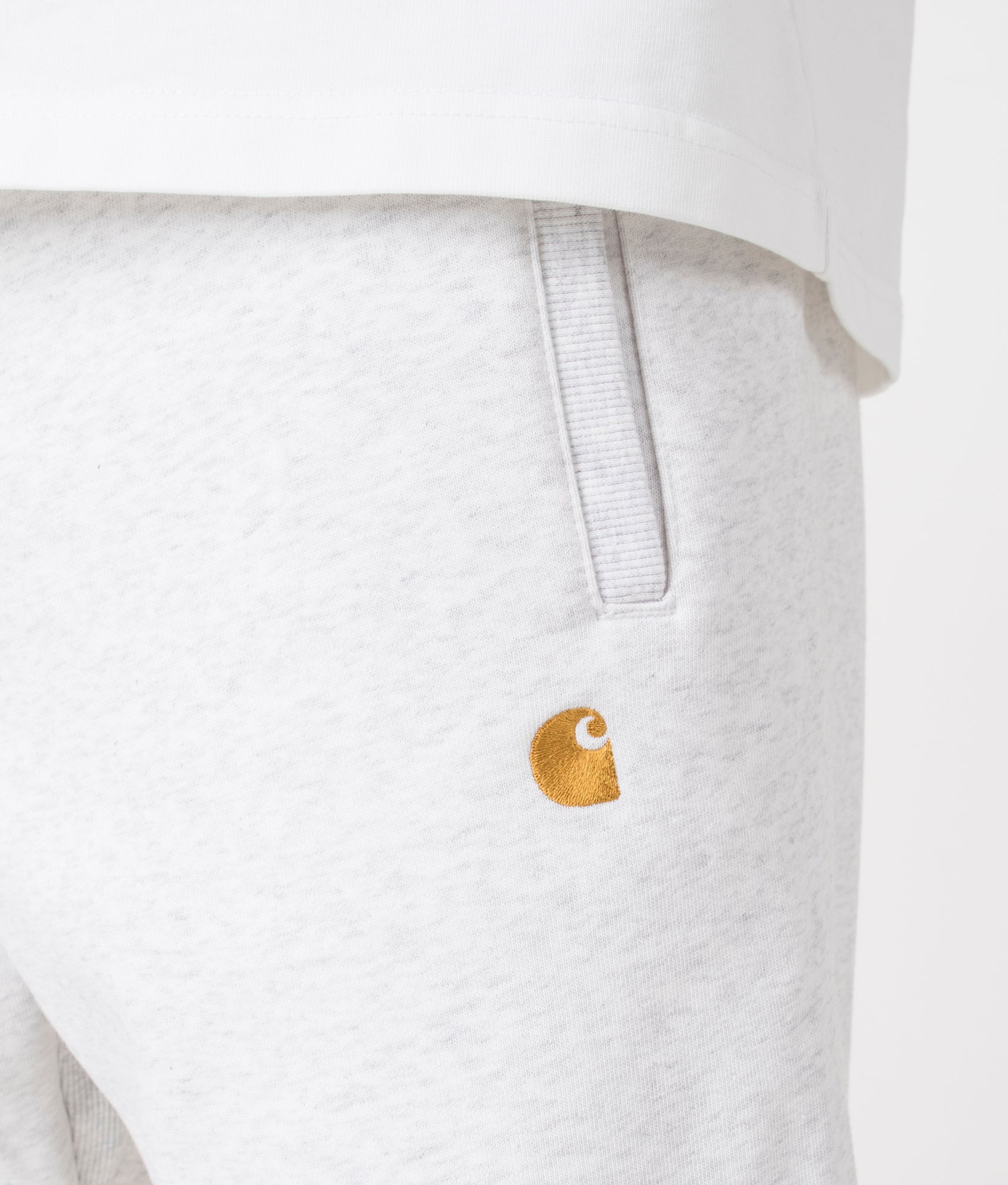 Carhartt WIP Relaxed Fit Chase Joggers in Ash Heather/Gold. Detail angle model shot at EQVVS.
