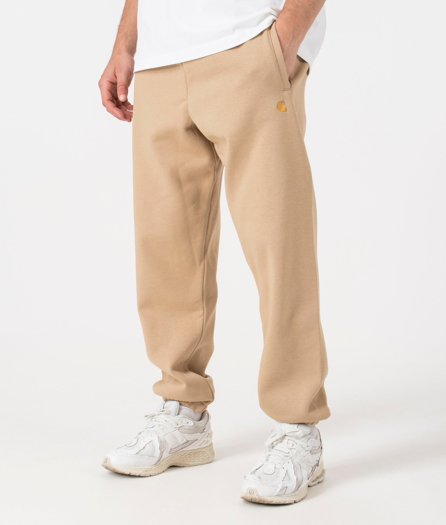Carhartt WIP Relaxed Fit Chase Joggers in Sable/Gold. Side angle model shot at EQVVS.