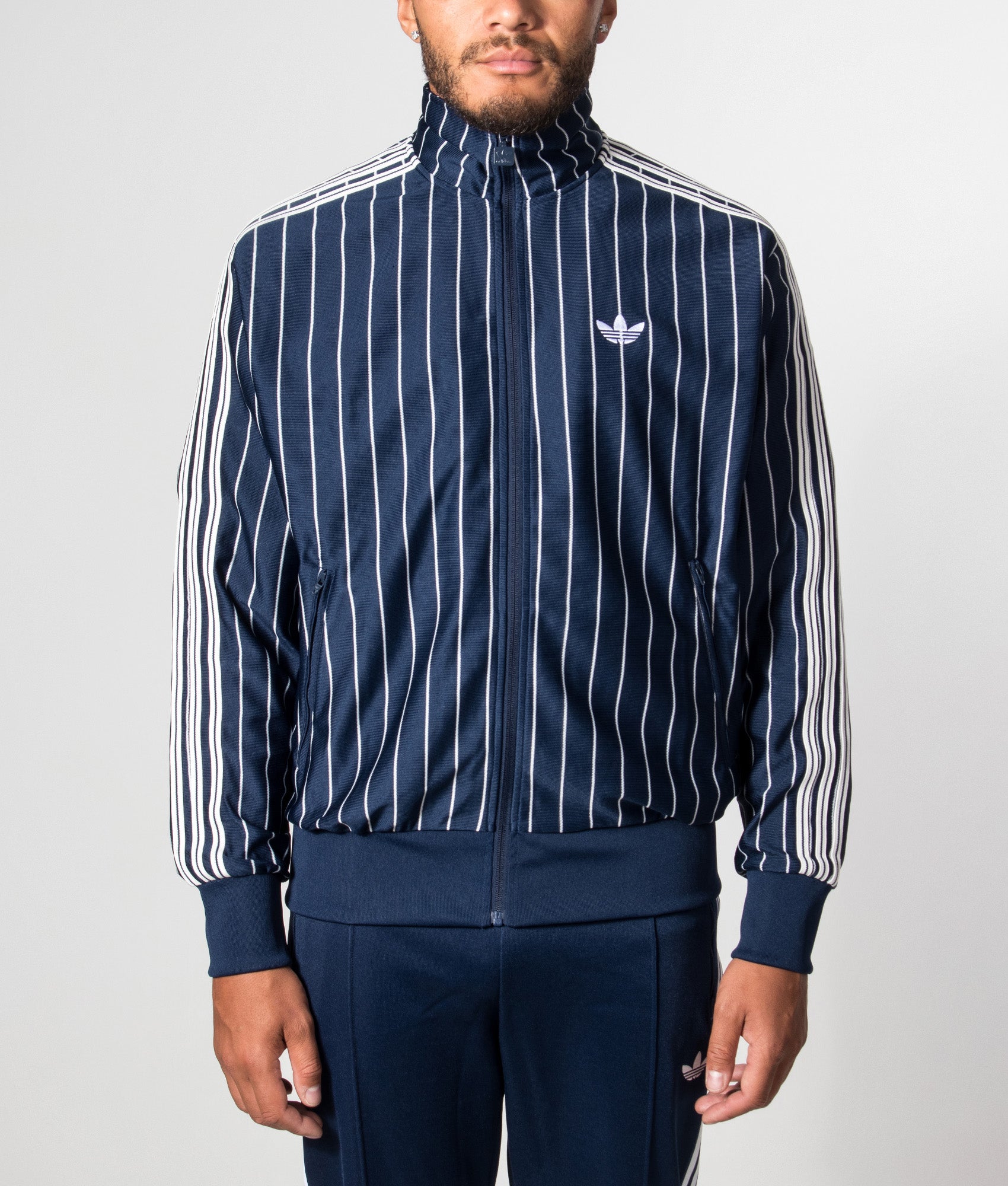 adidas Originals Loose Fit Firebird Pinstripe Track Top in Night Indigo at EQVVS Menswear. Model front shot.