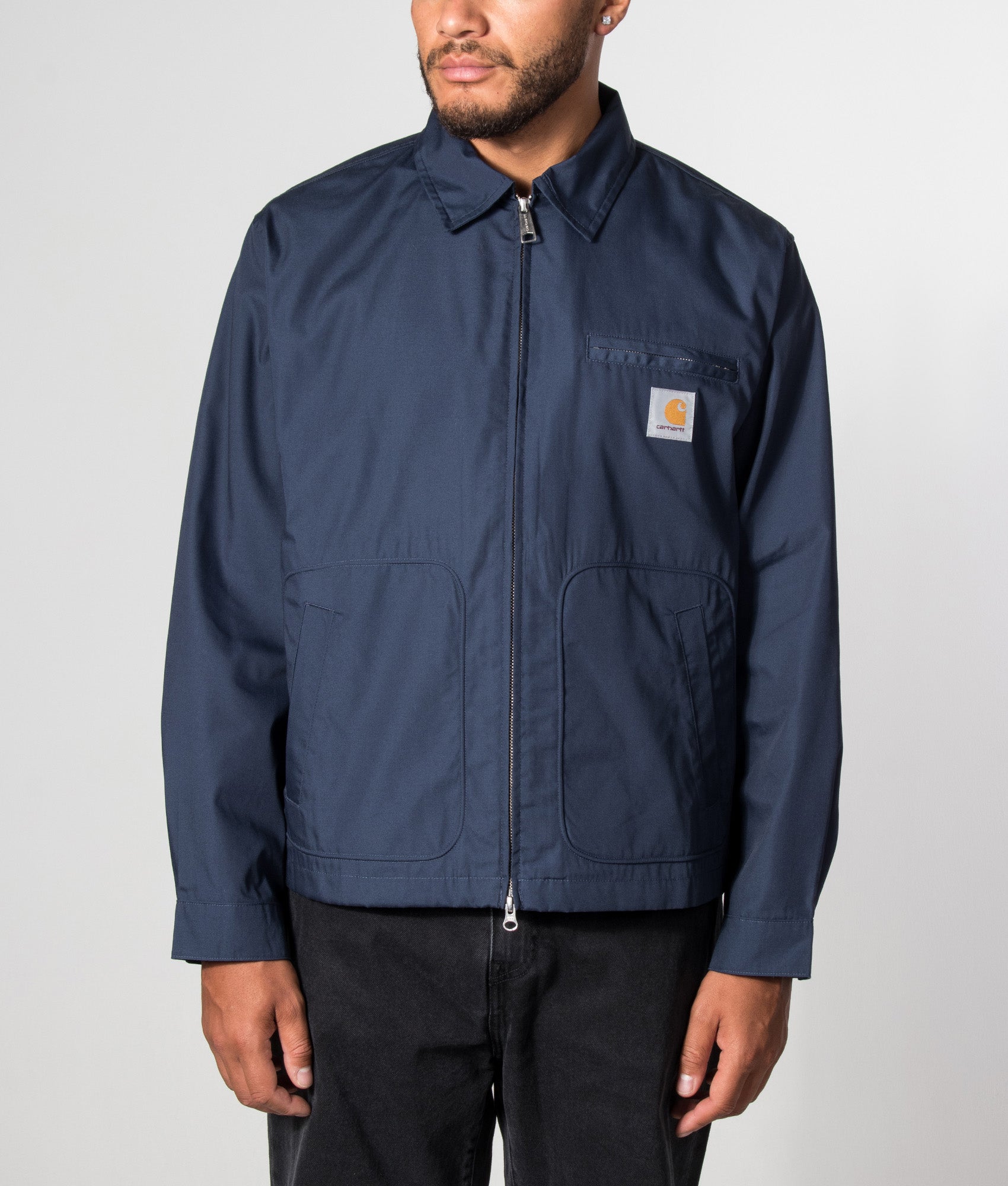Carhartt WIP Postal Jacket in Blue at EQVVS Menswear. Model front shot.