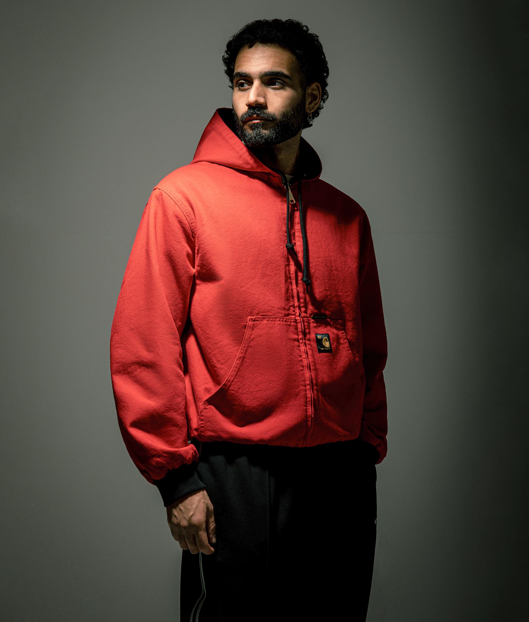 Carhartt WIP 50 Years Anniversary OG Active Canvas Jacket in Black/USA Red at EQVVS Menswear. Side B campaign shot.