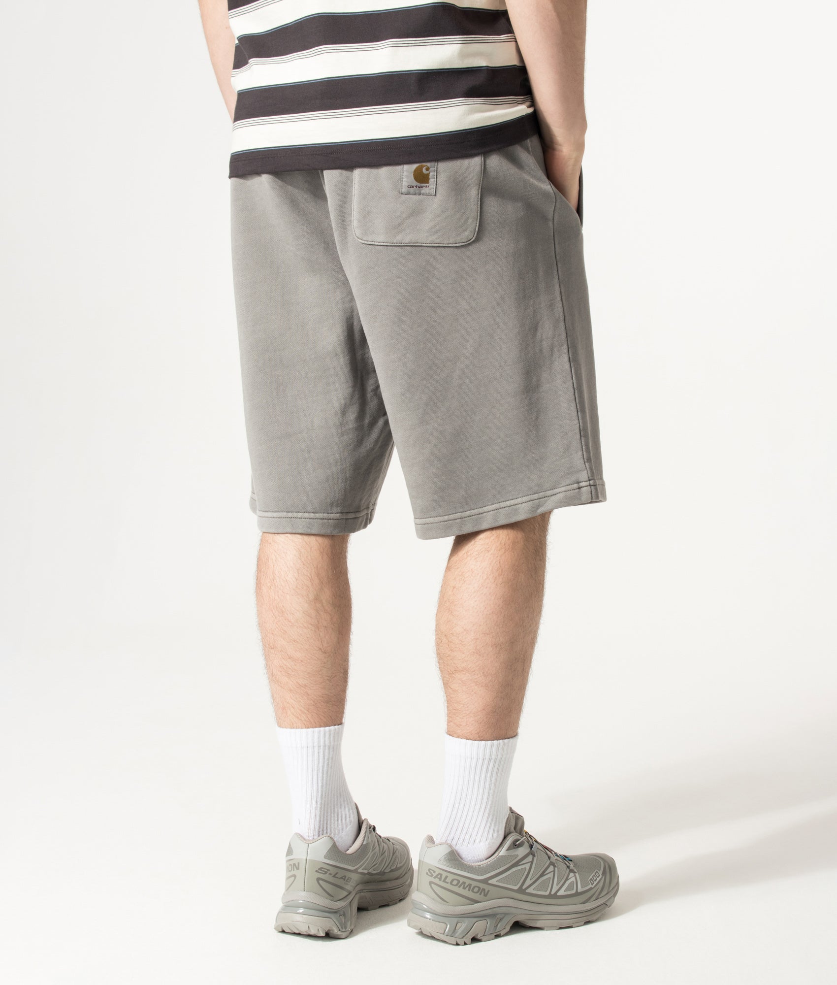 Carhartt WIP Balloon Fit Nelson Sweat Shorts in Yosemite at EQVVS Menswear. Angled model back shot.