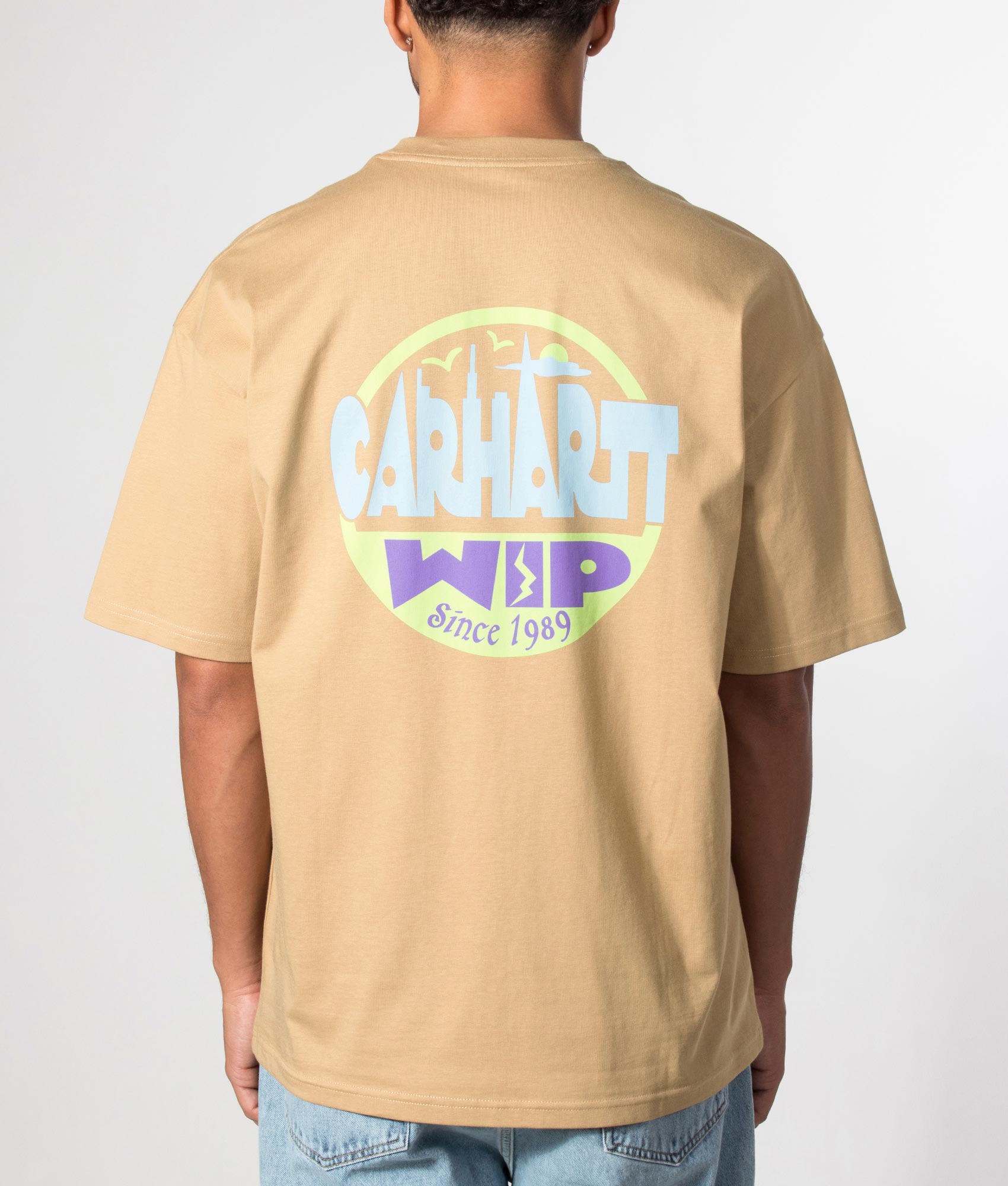 Carhartt WIP Oversized Fit Luggage Label T-Shirt in Dusty H Brown at EQVVS Menswear. Model back shot.