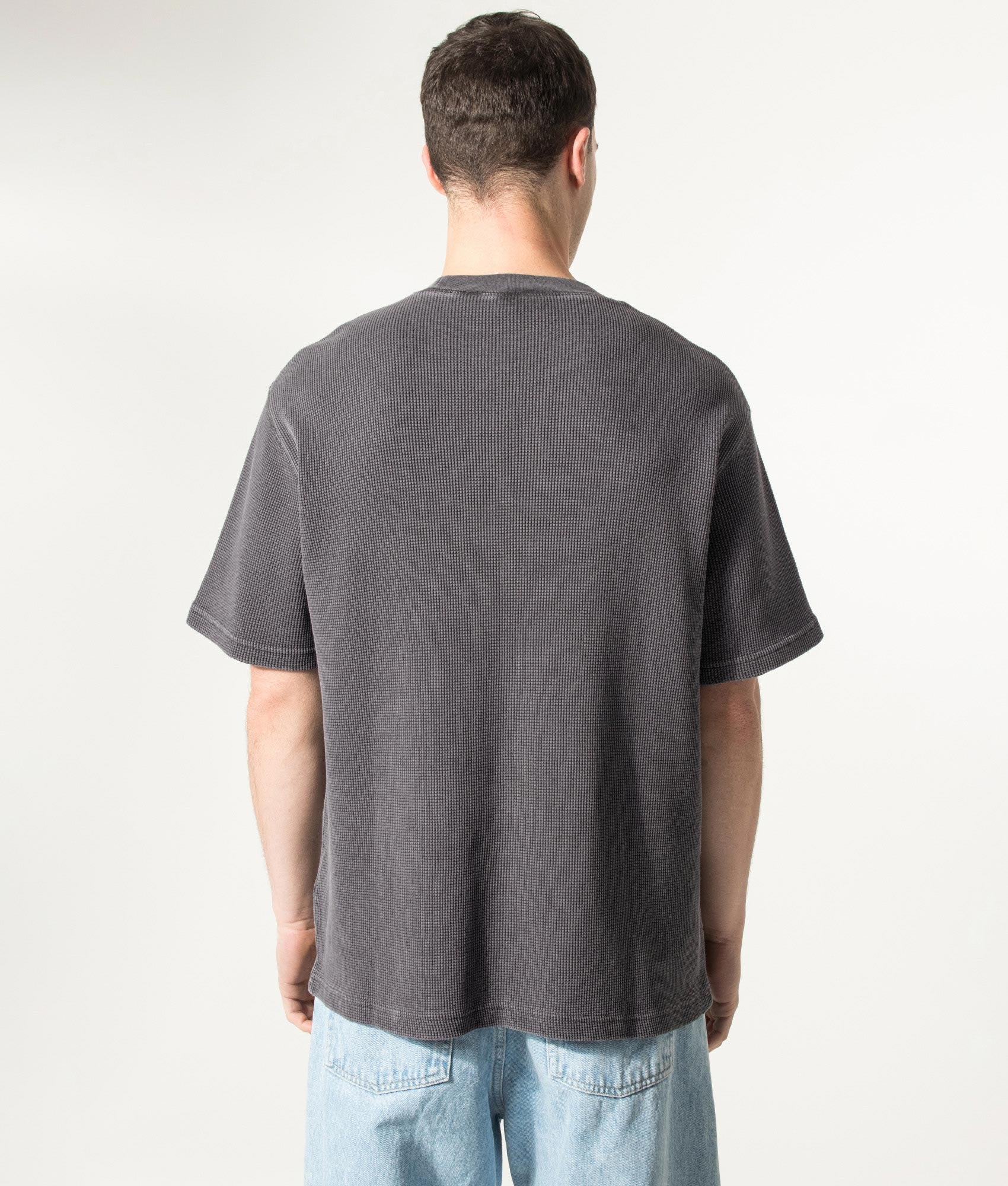 Carhartt WIP Relaxed Fit Nelson Waffle T-Shirt in Black at EQVVS Menswear. Model back shot.