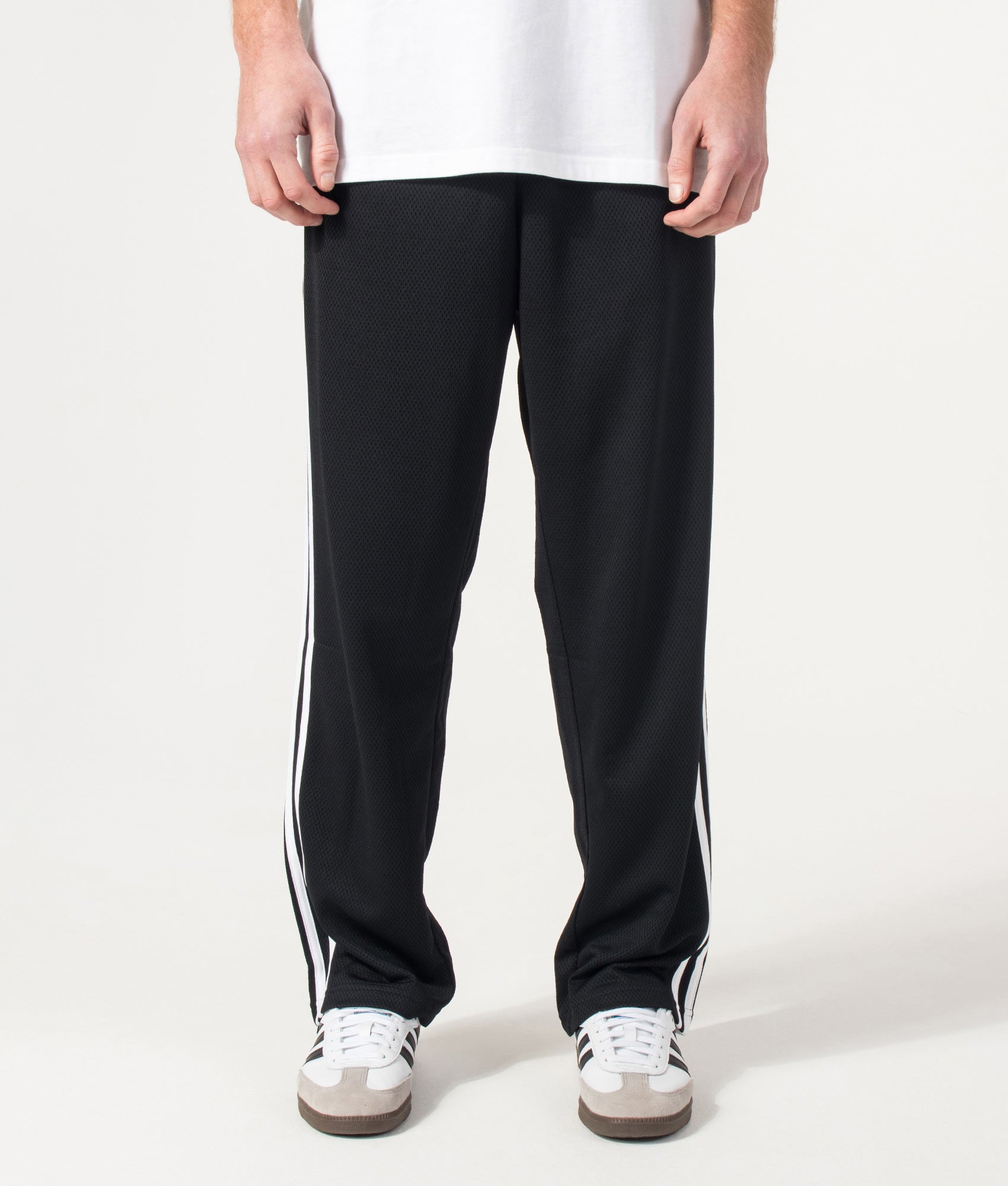 adidas Originals Firebird Track Pants in Black at EQVVS Menswear. Model front shot.