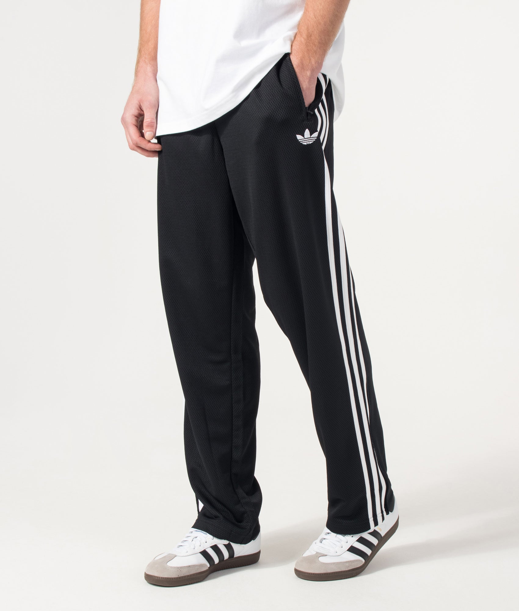 adidas Originals Firebird Track Pants in Black at EQVVS Menswear. Angled model front shot.