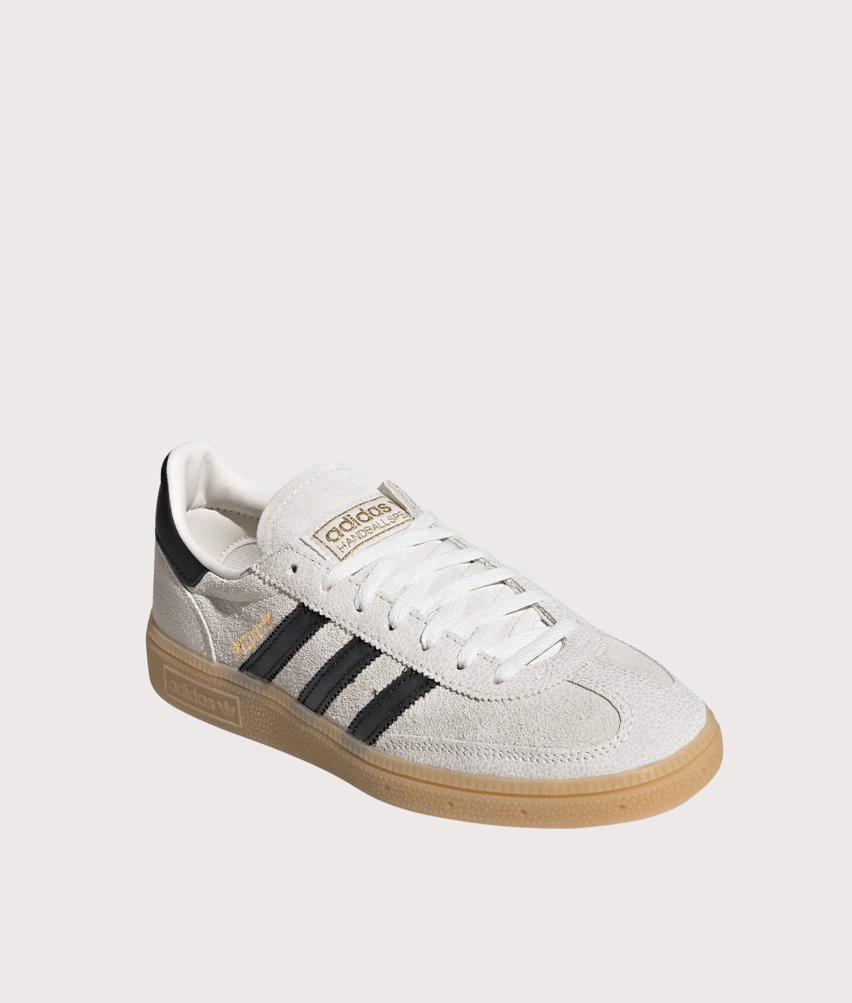 adidas Originals Handball Spezial Trainers in Cloud White, Core Black and Gold Metallic at EQVVS Menswear. Angled front shot.