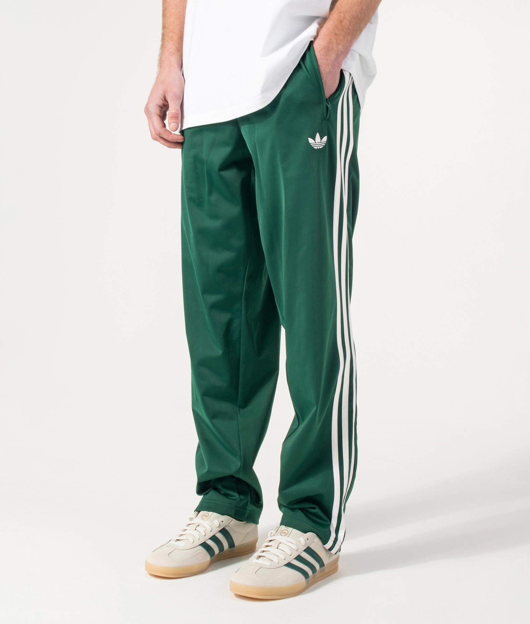 adidas Originals Firebird Track Pants in Collegiate Green at EQVVS Menswear. Angled model front shot.