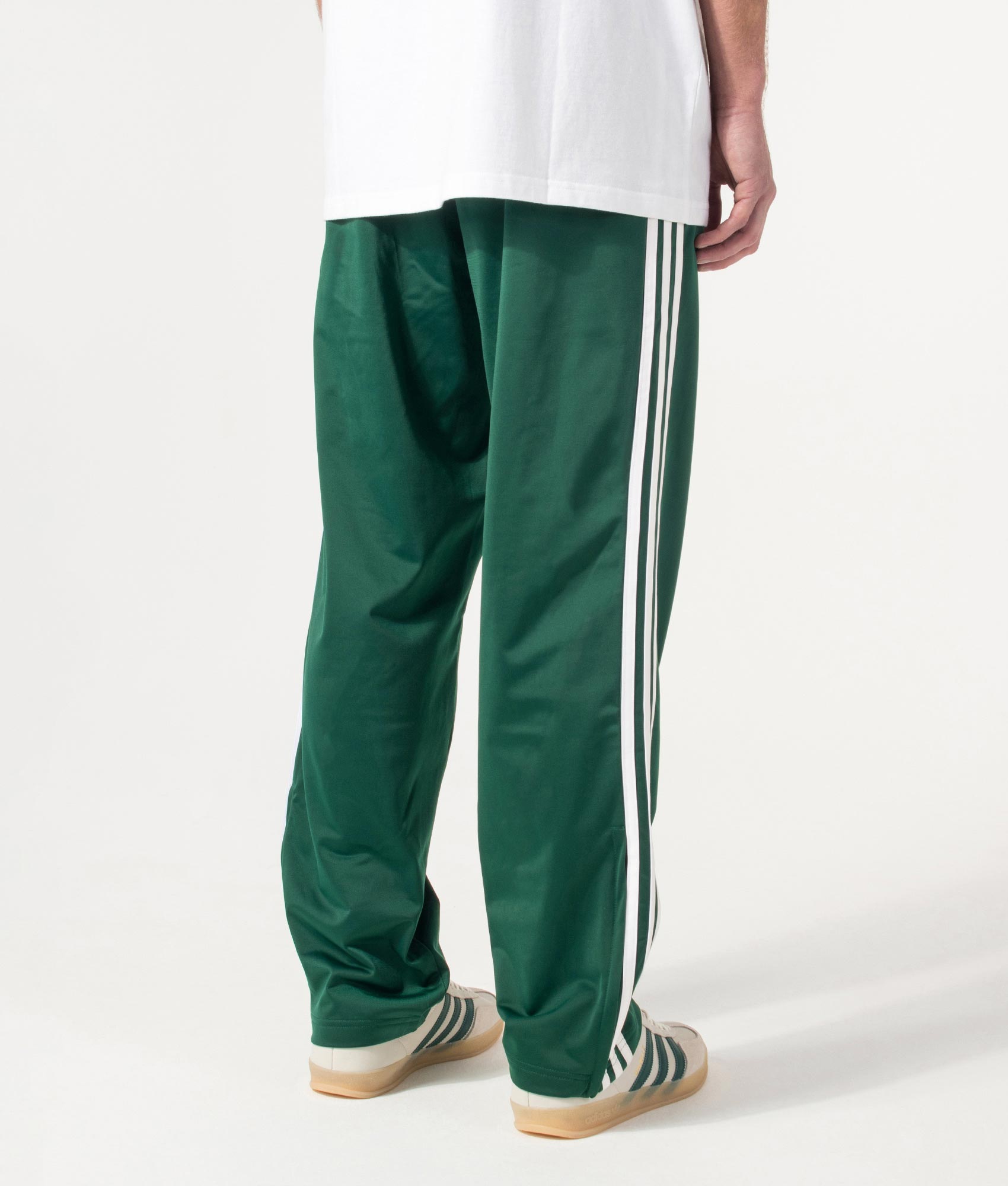 adidas Originals Firebird Track Pants in Collegiate Green at EQVVS Menswear. Angled model back shot.