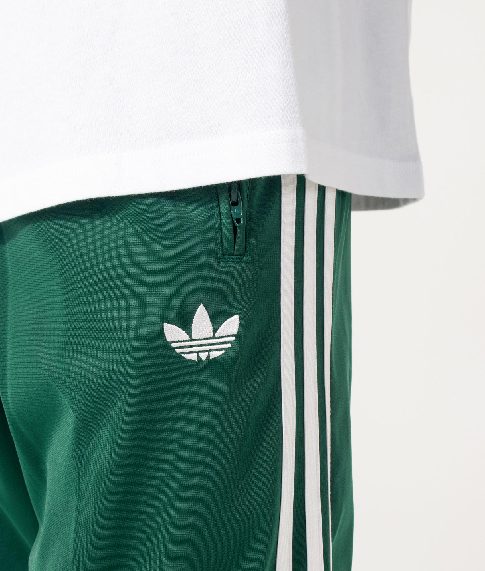 adidas Originals Firebird Track Pants in Collegiate Green at EQVVS Menswear. Detail shot.