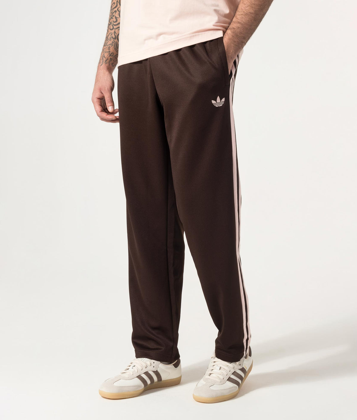 adidas Originals Regular Fit SST Track Pants in Aurora Coffee at EQVVS Menswear. Angled model front shot.