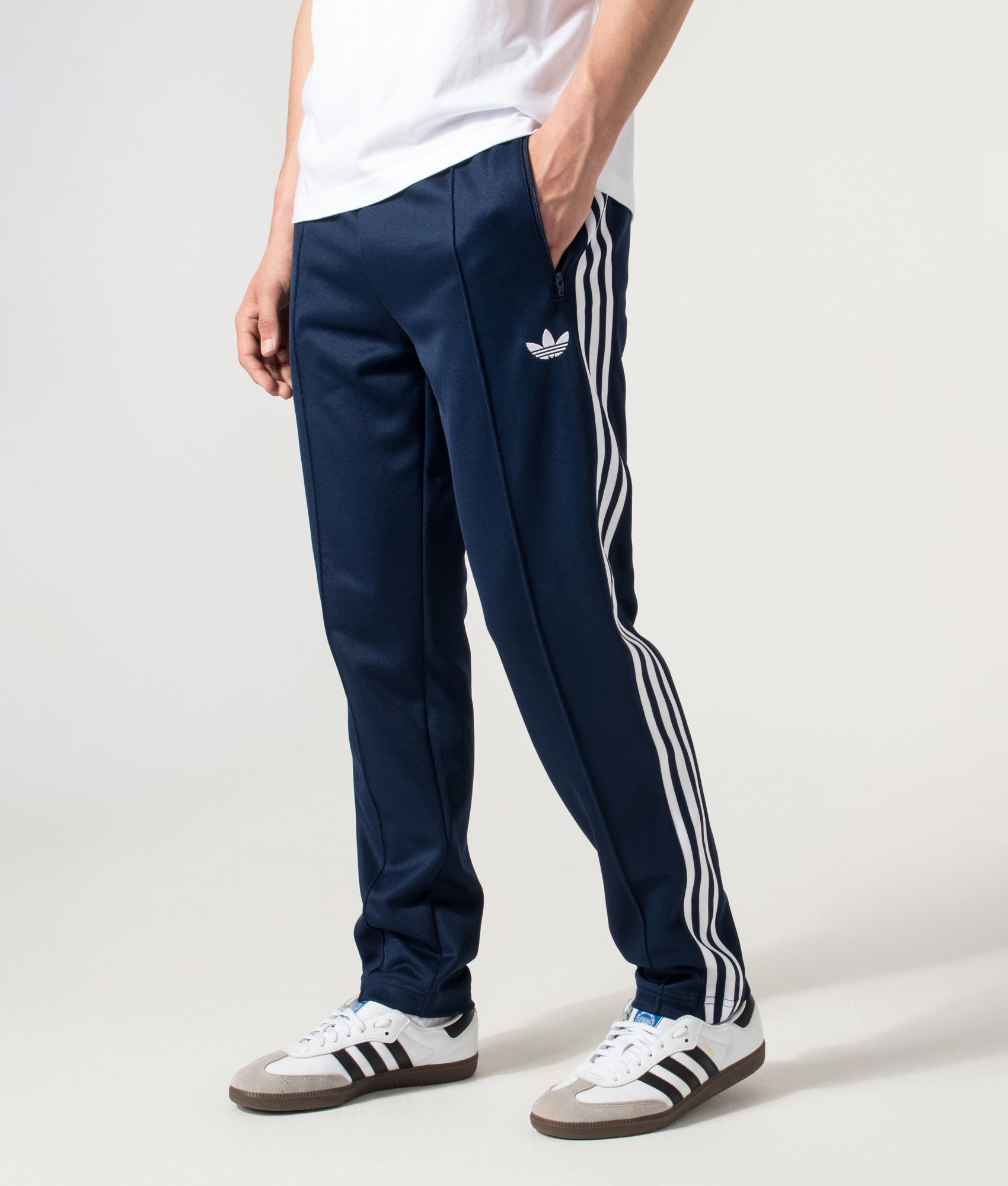 adidas Originals Slim Fit Beckenbauer Track Pants in Night Indigo at EQVVS Menswear. Angled model front shot.