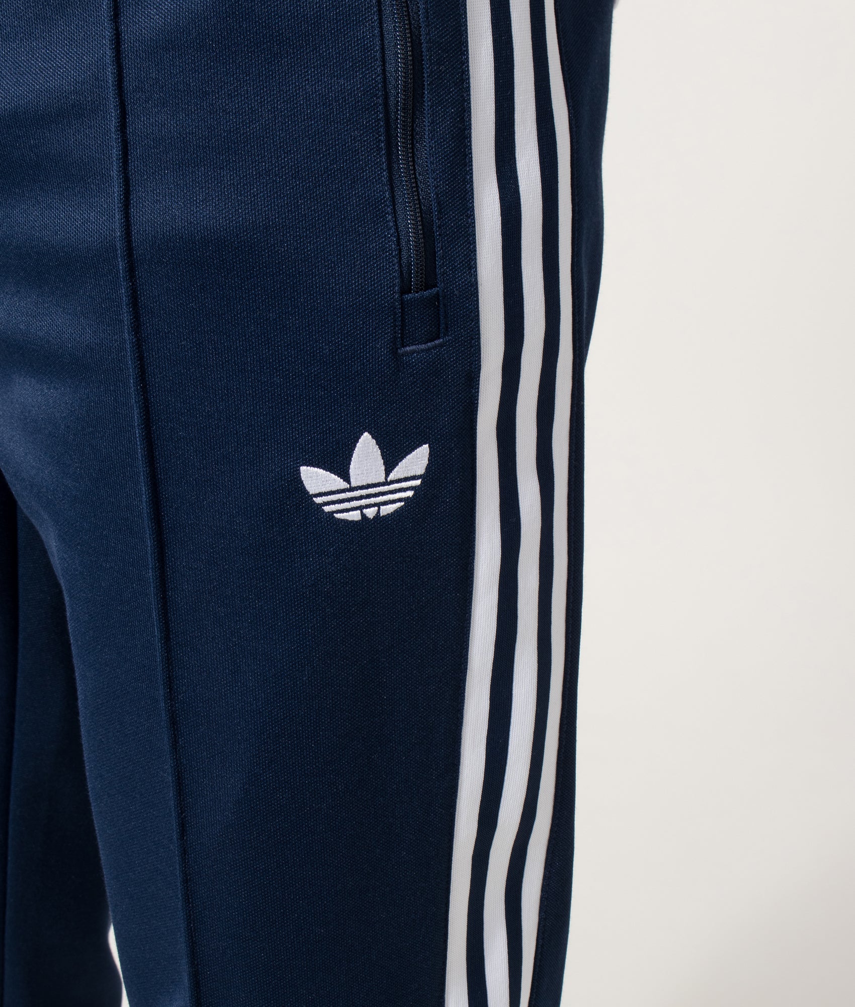 adidas Originals Slim Fit Beckenbauer Track Pants in Night Indigo at EQVVS Menswear. Detail shot.