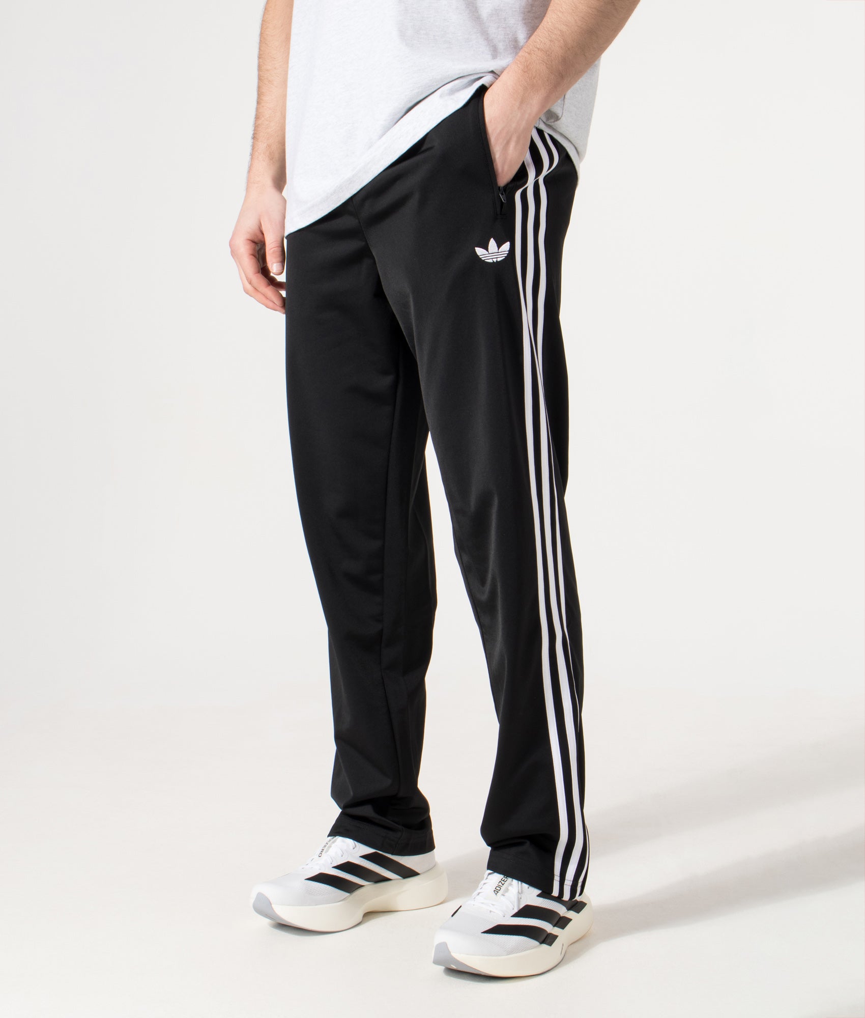 adidas Originals Firebird Track Pants in Black at EQVVS Menswear. Angled model front shot.