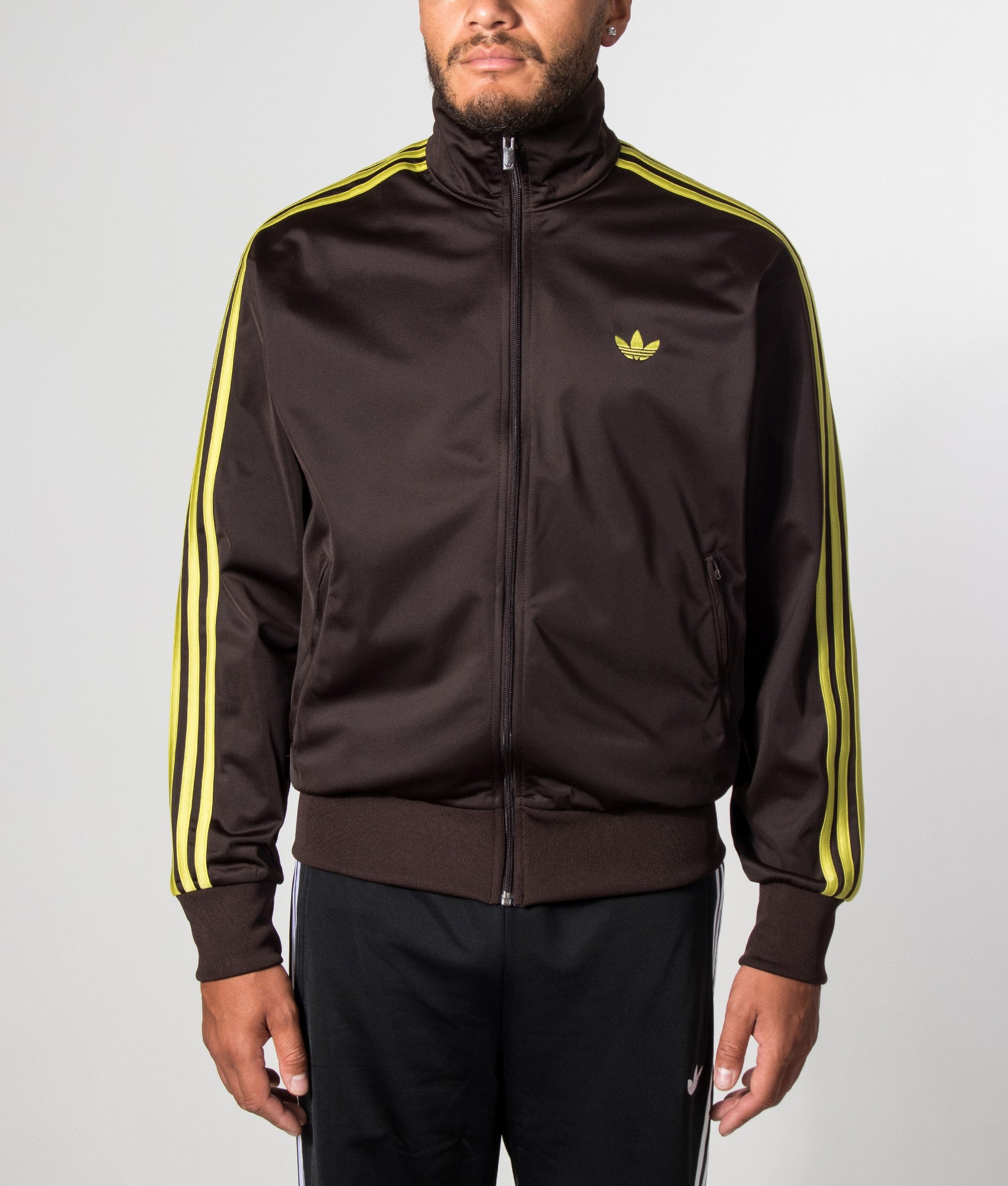 adidas Originals Loose Fit Firebird Track Top in Aurora Coffee and Preloved Lime at EQVVS Menswear. Model front shot.