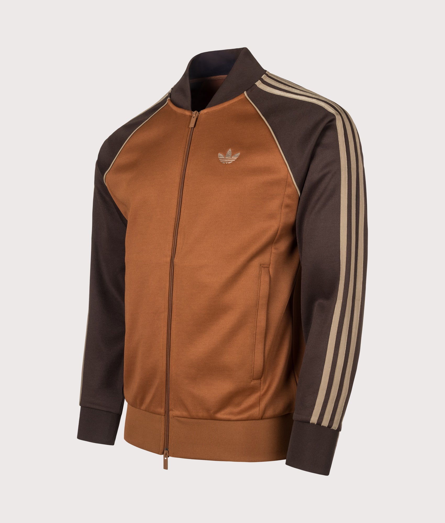 adidas Originals SST Track Top in Dust Brown at EQVVS Menswear. Angled front shot.