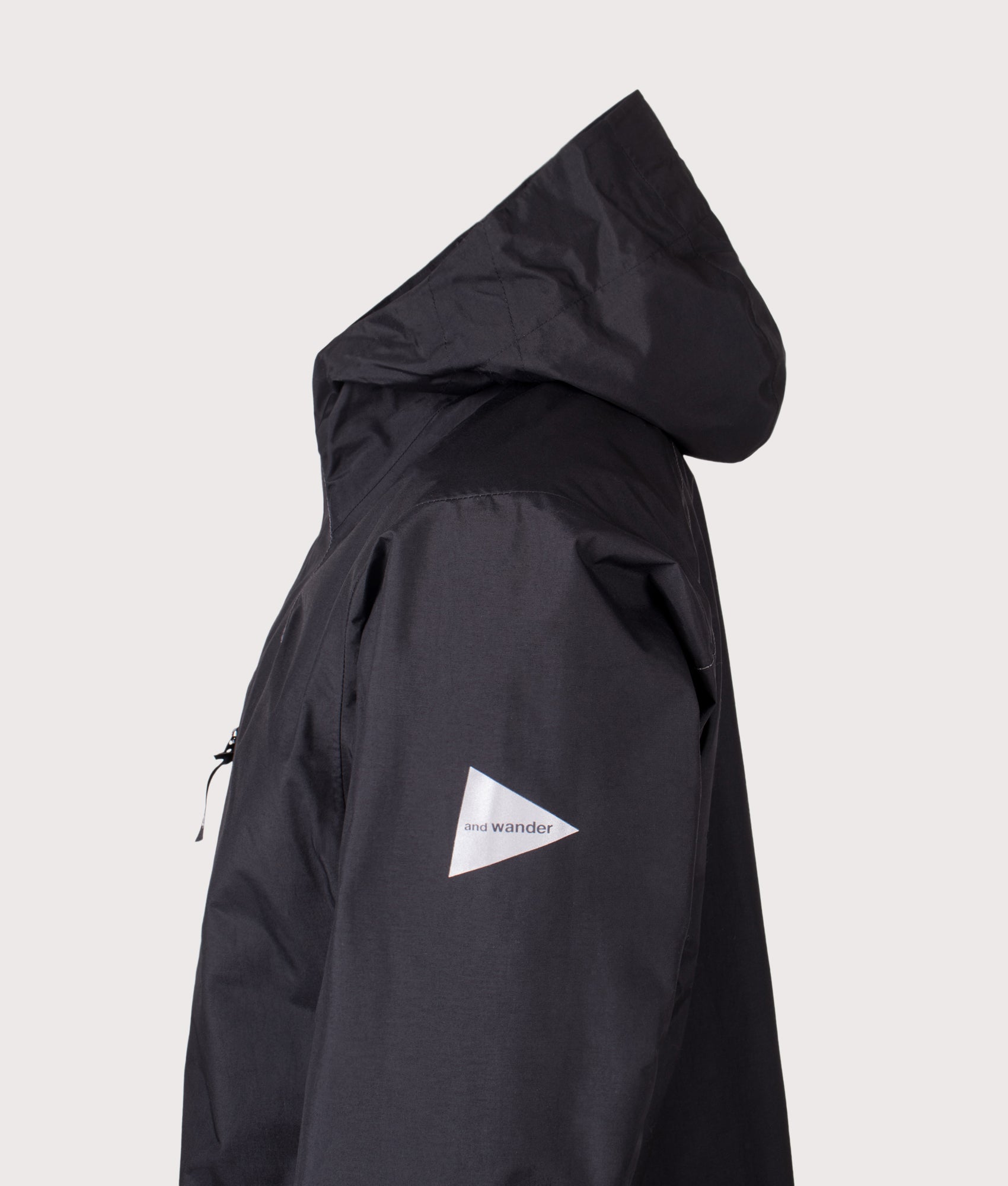 And Wander 2.5L Hiker Rain Jacket in Black at EQVVS Menswear. Side detail shot.