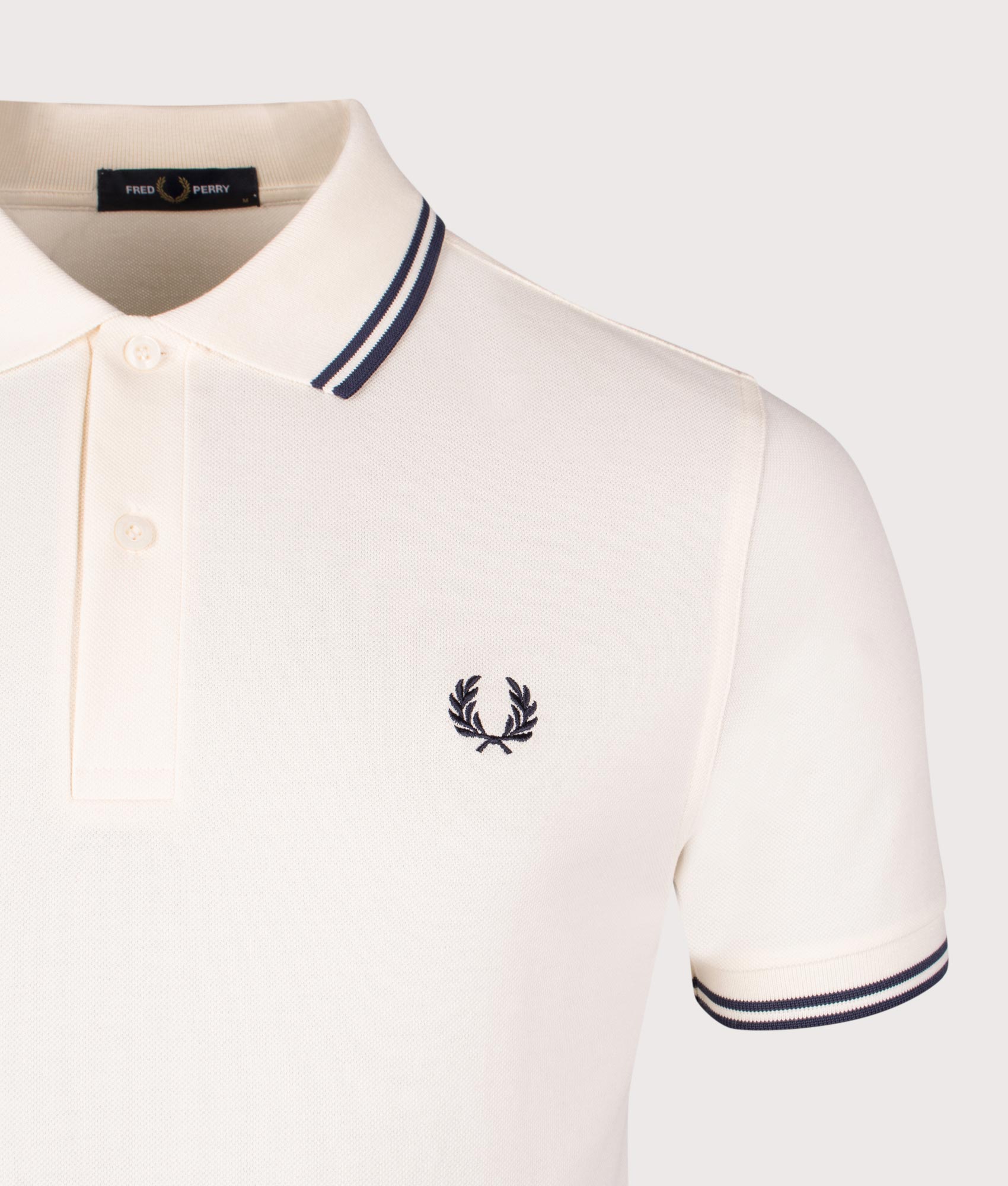 Fred Perry Twin Tipped Polo Shirt in Ecru/Tennis Blue, 100% Cotton at EQVVS. Close-up shot.