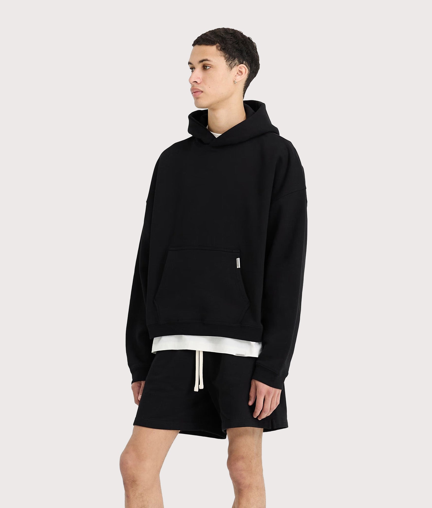 REPRESENT Initial Boxy Oversized Hoodie in black at EQVVS Menswear. Angled model front shot.