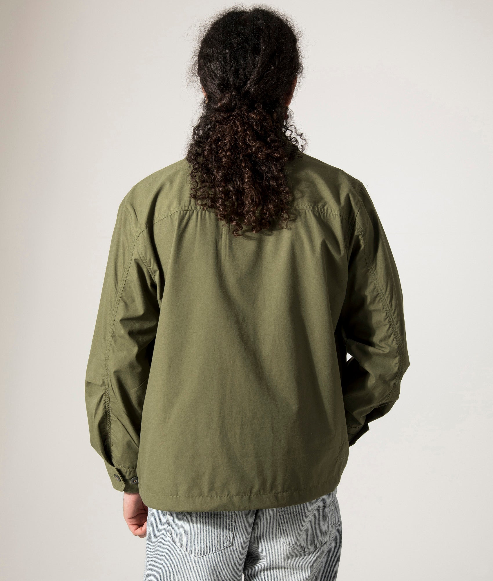 Universal Works Parachute Field Jacket in Olive. Shot at EQVVS. Model back shot. 