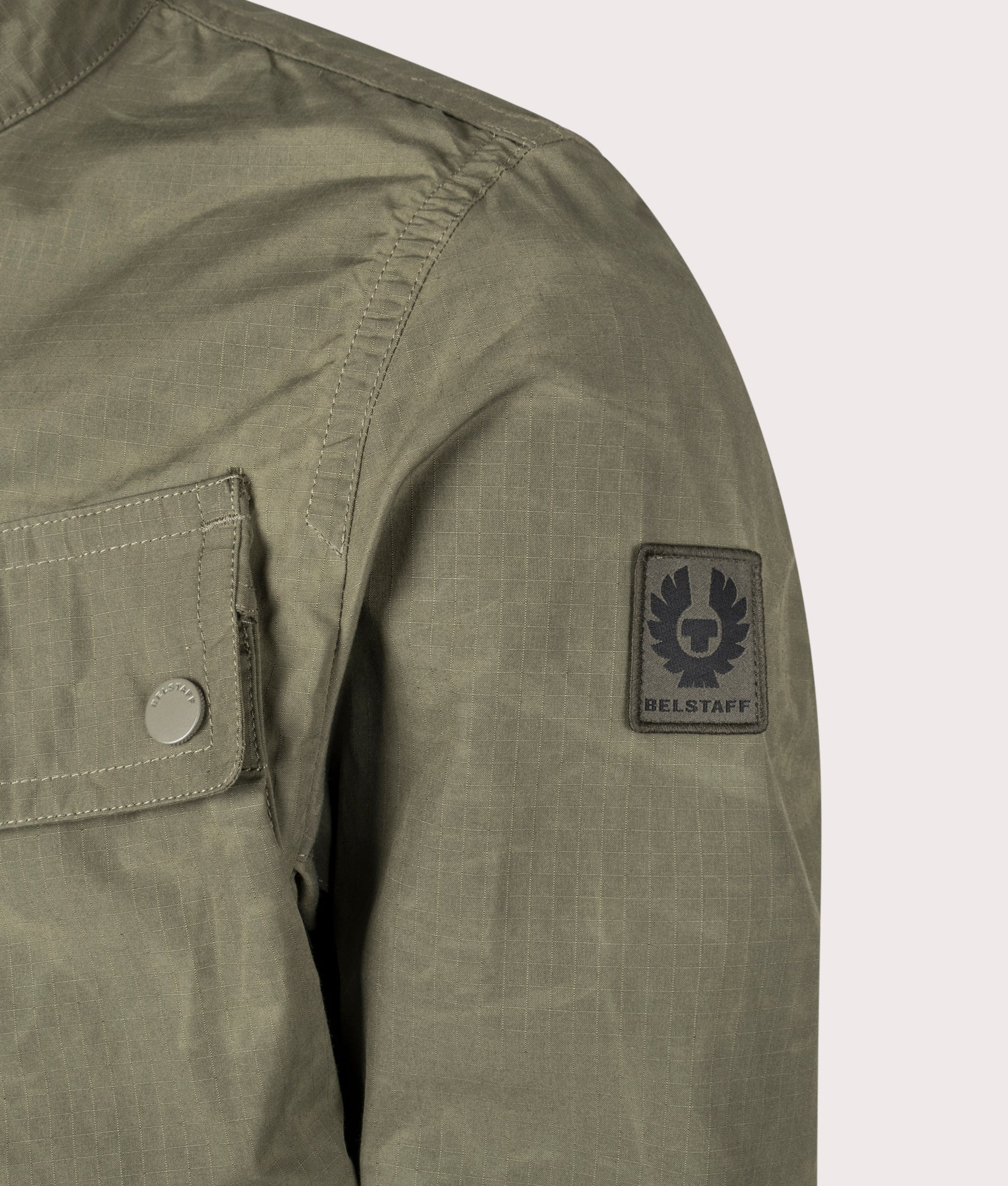 Belstaff Service Racemaster Jacket in Surplus Green at EQVVS. Detailed logo shot. 