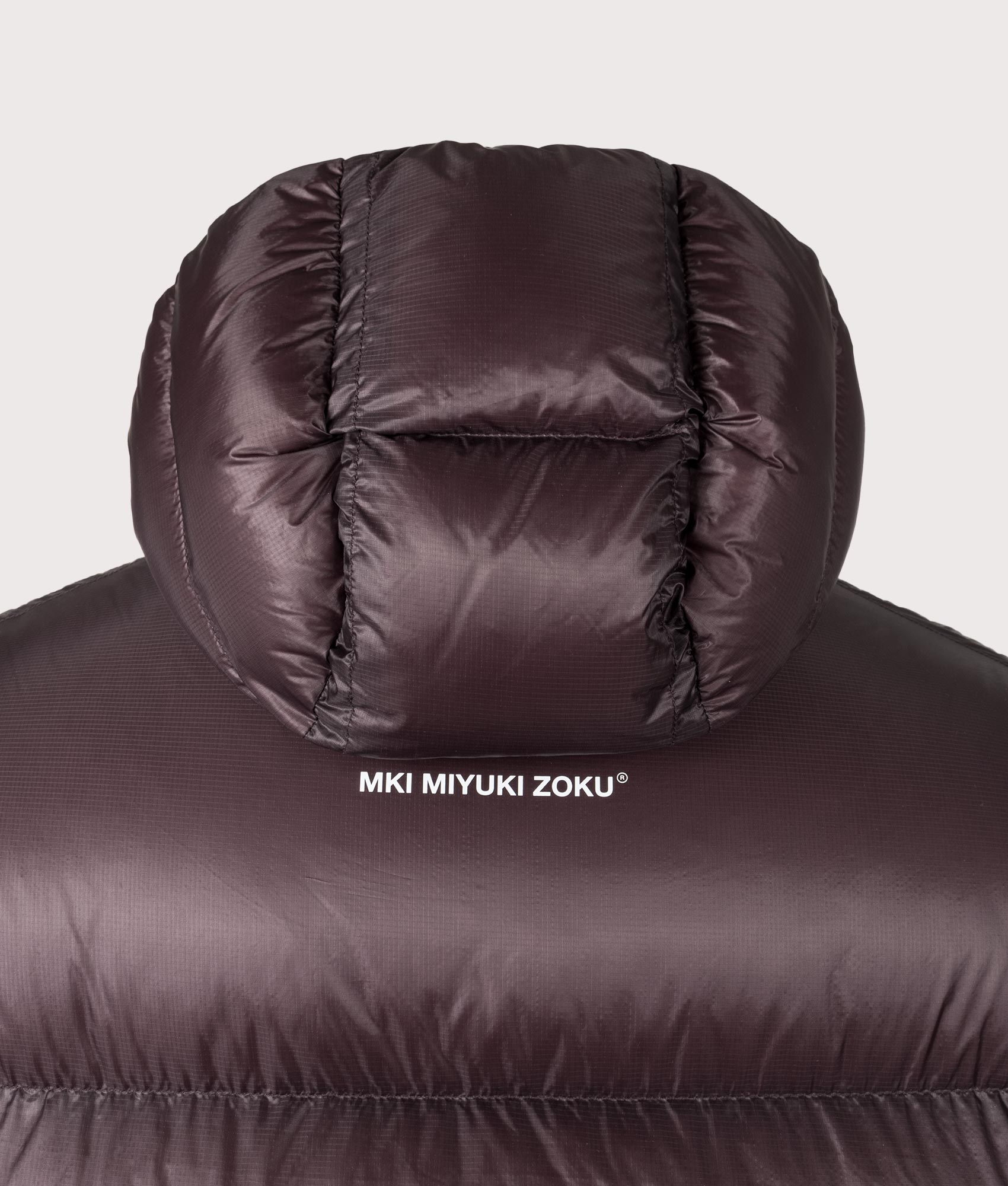 MKI MIYUKI ZOKU Translucent Hooded Bubble Jacket in Raisin at EQVVS Menswear. Detail shot.