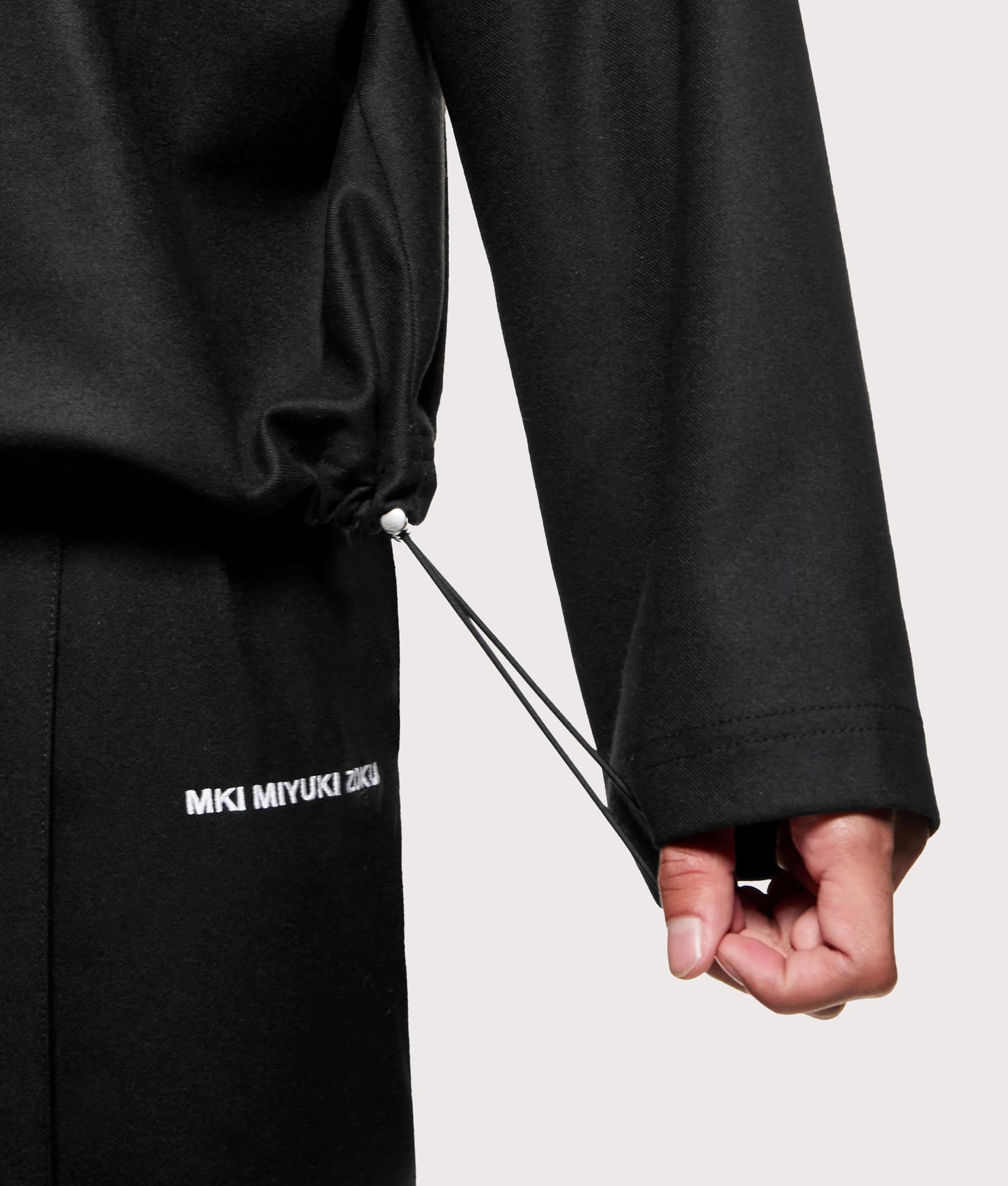 MKI MIYUKI ZOKU Suiting Quarter zip Sweatshirt in Black at EQVVS Menswear. Hem detail shot.