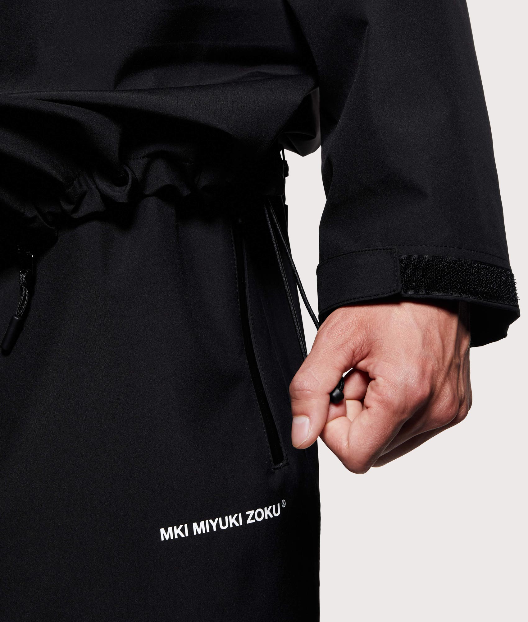 MKI MIYUKI ZOKU V3 Shell Hooded Jacket in Black at EQVVS Menswear. Hem detail shot.