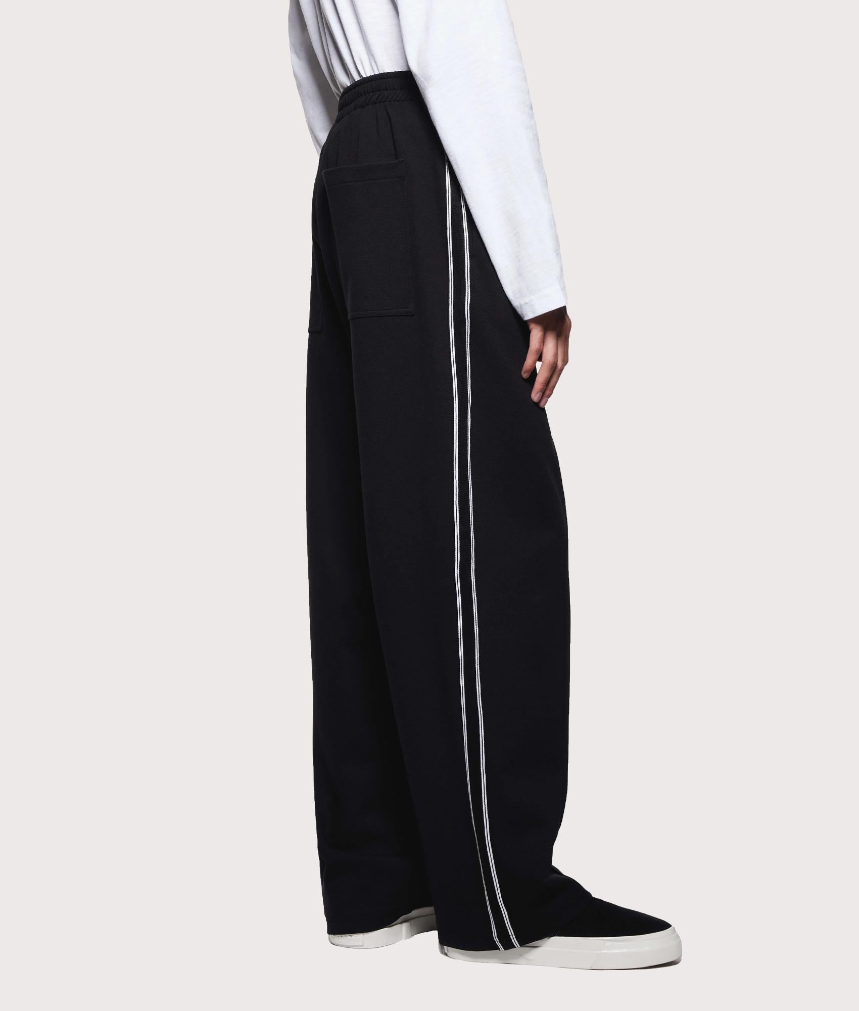 MKI MIYUKI ZOKU Wide Fit Track Pants in core black at EQVVS Menswear. Model side shot.