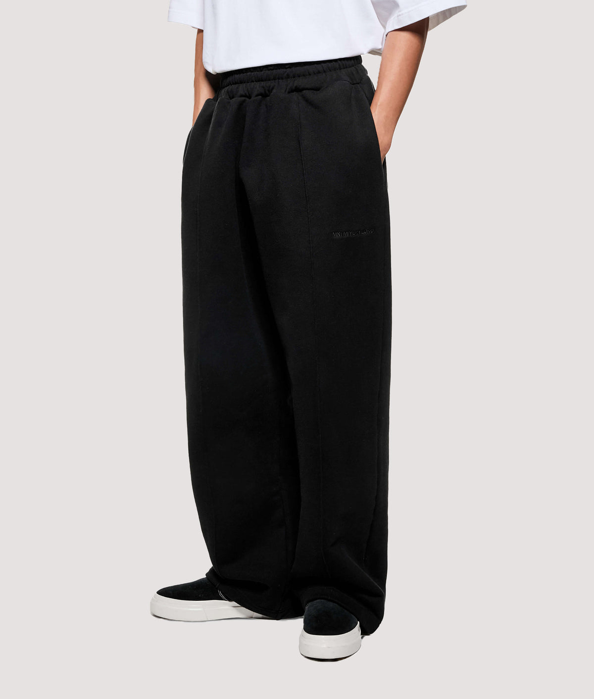 MKI MIYUKI ZOKU Relaxed Fit 800 GSM Superweight Wide Leg Joggers in Black at EQVVS Menswear. Angled model front shot.